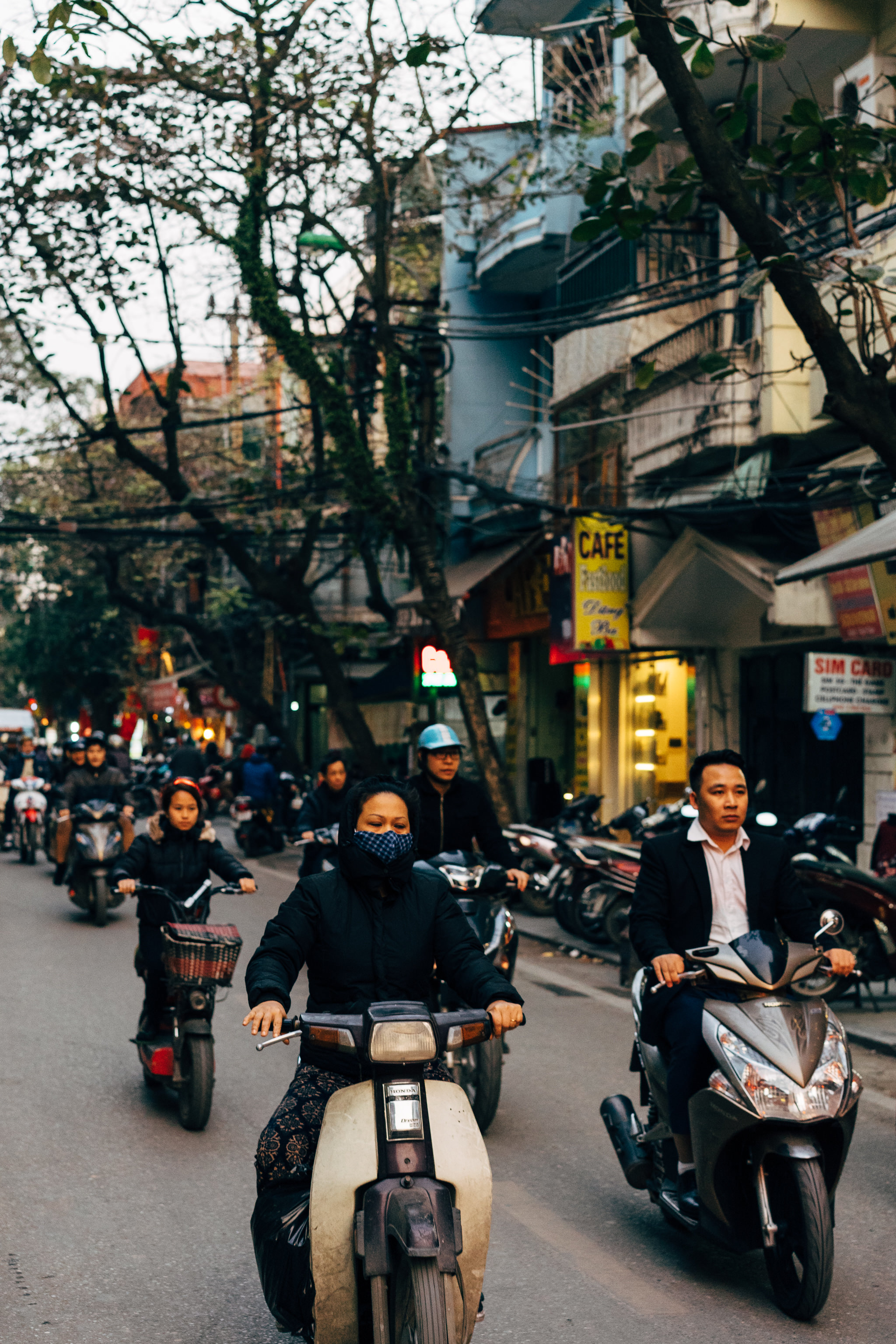 Busy Vietnam street scene with multiple people riding scooters.
