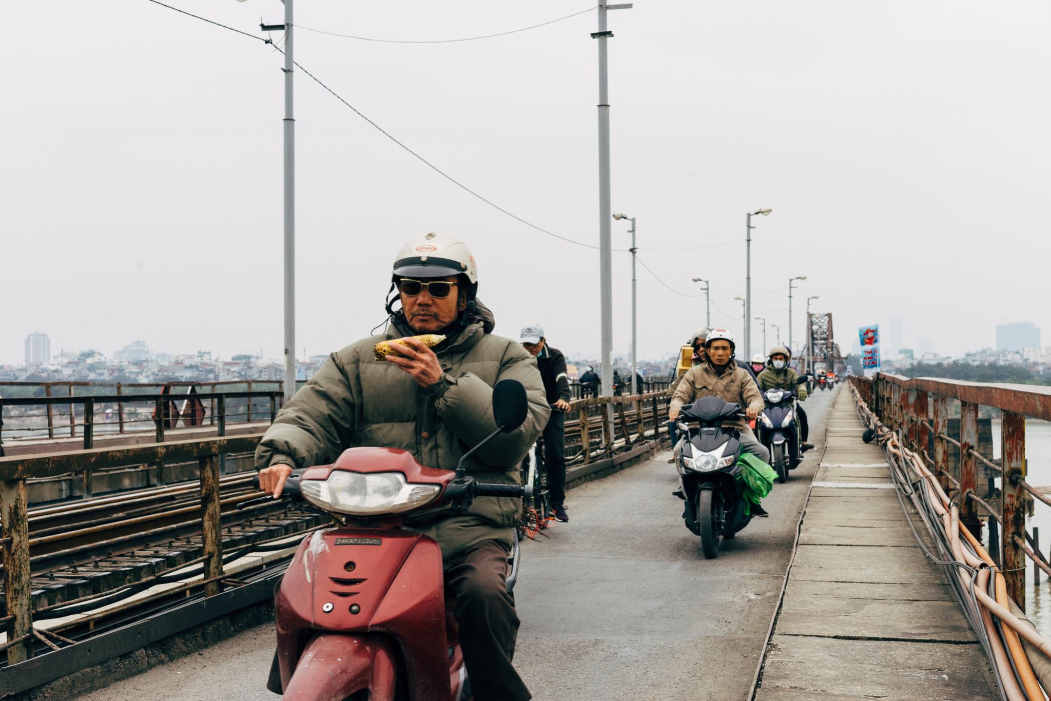 Man holding a corn on a motor scooter