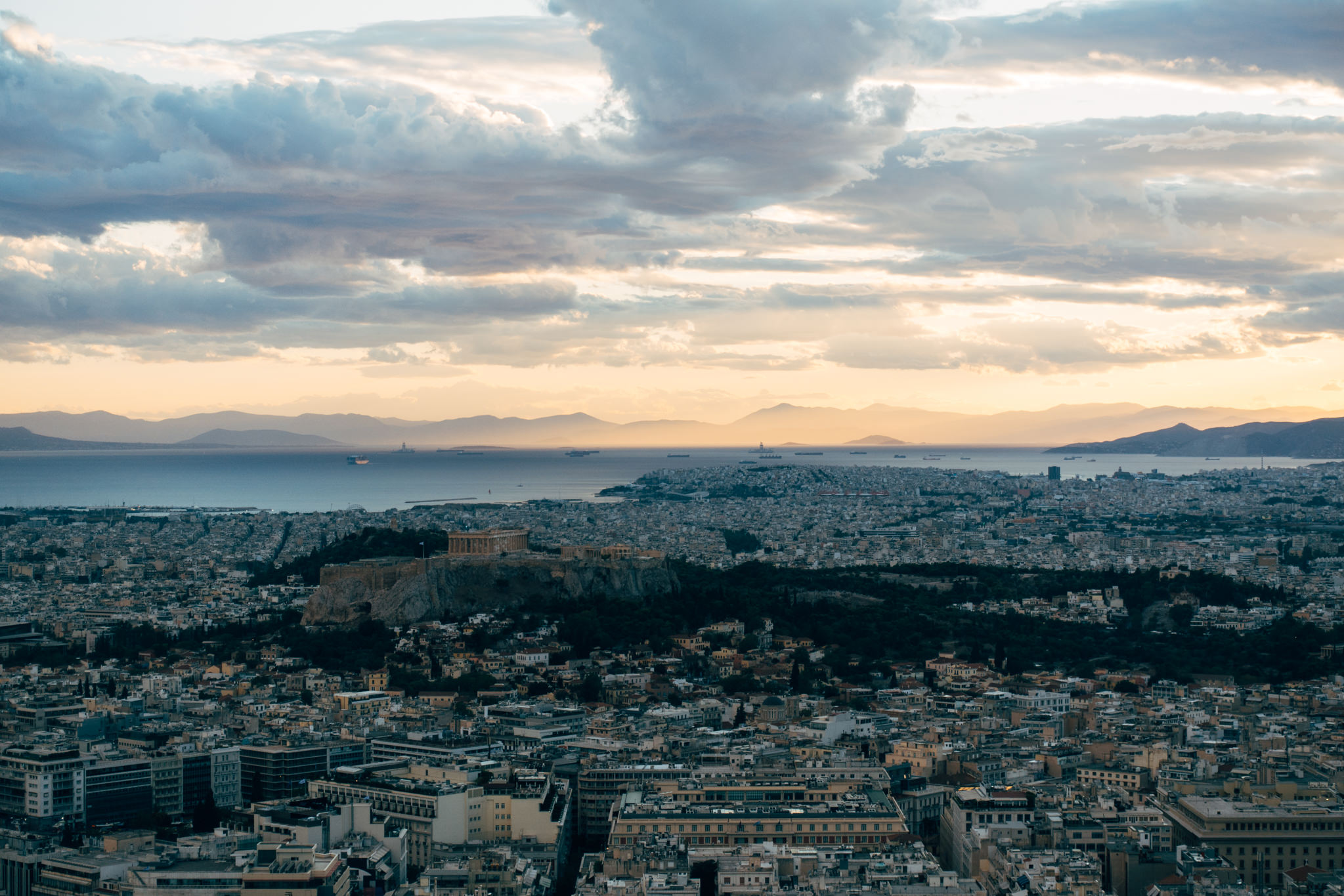Sunset view of Athens, Greece, with the Acropolis and the Aegean Sea in the background.