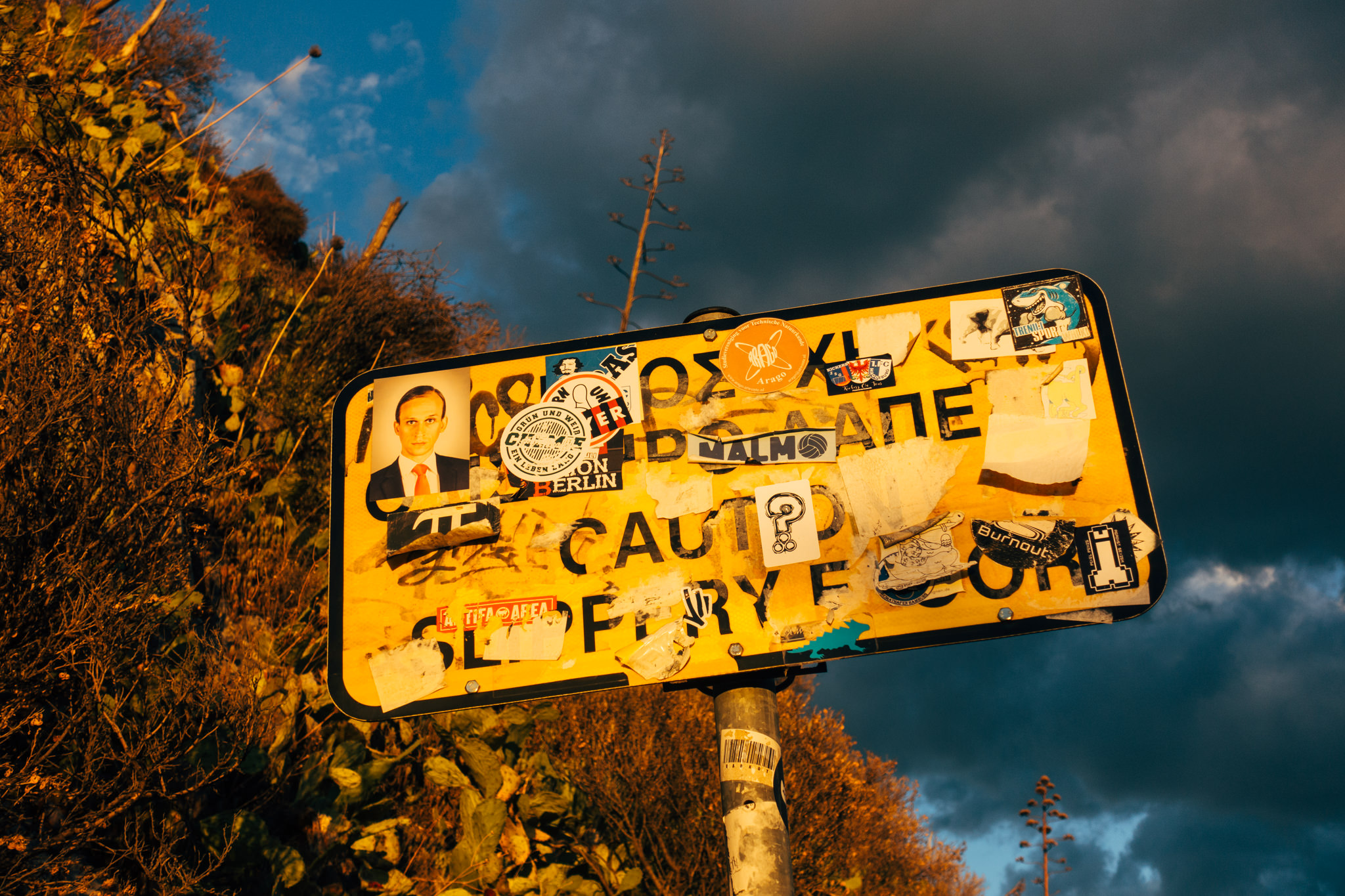 A yellow caution sign covered in stickers.