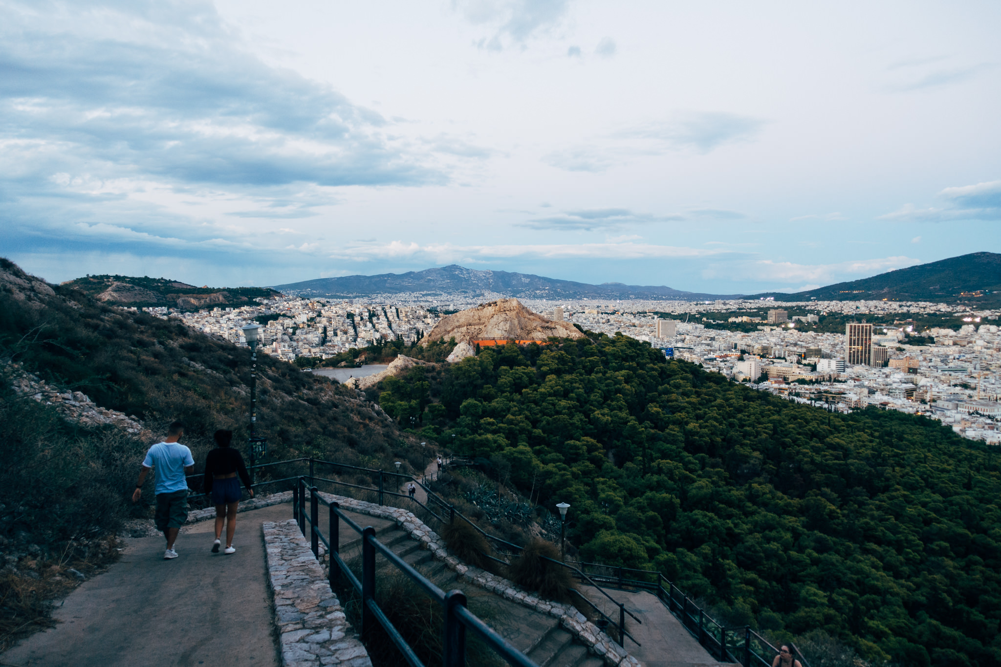 Couple walking down stone steps overlooking Athens, Greece.