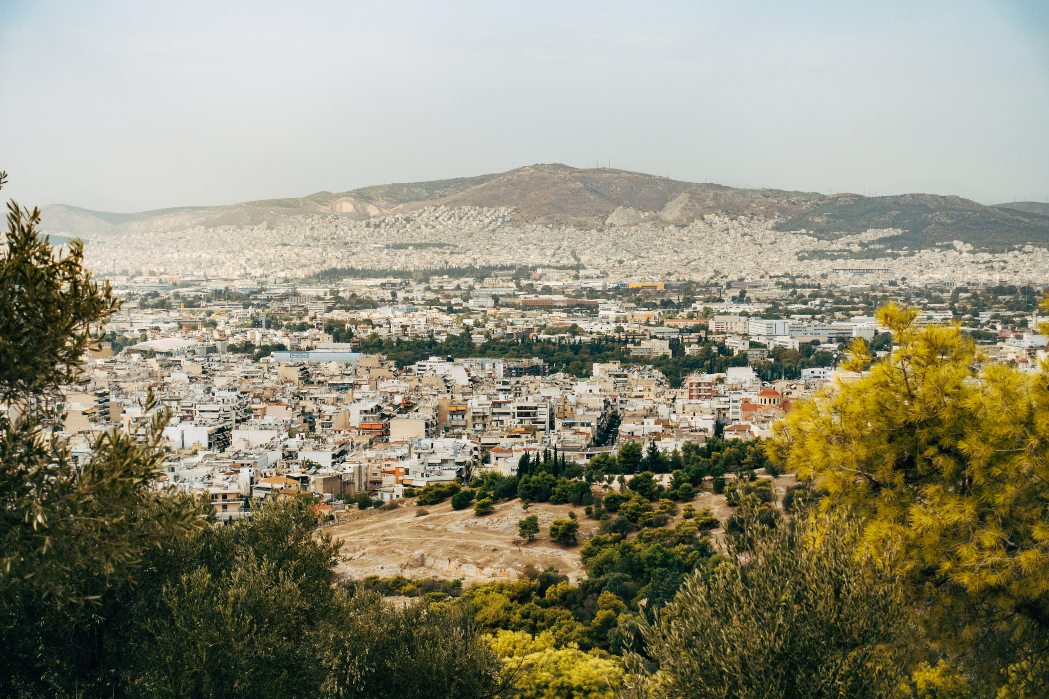 Panoramic view of Athens, Greece, from Filopappou Hill, showing the city sprawling beneath a hill.