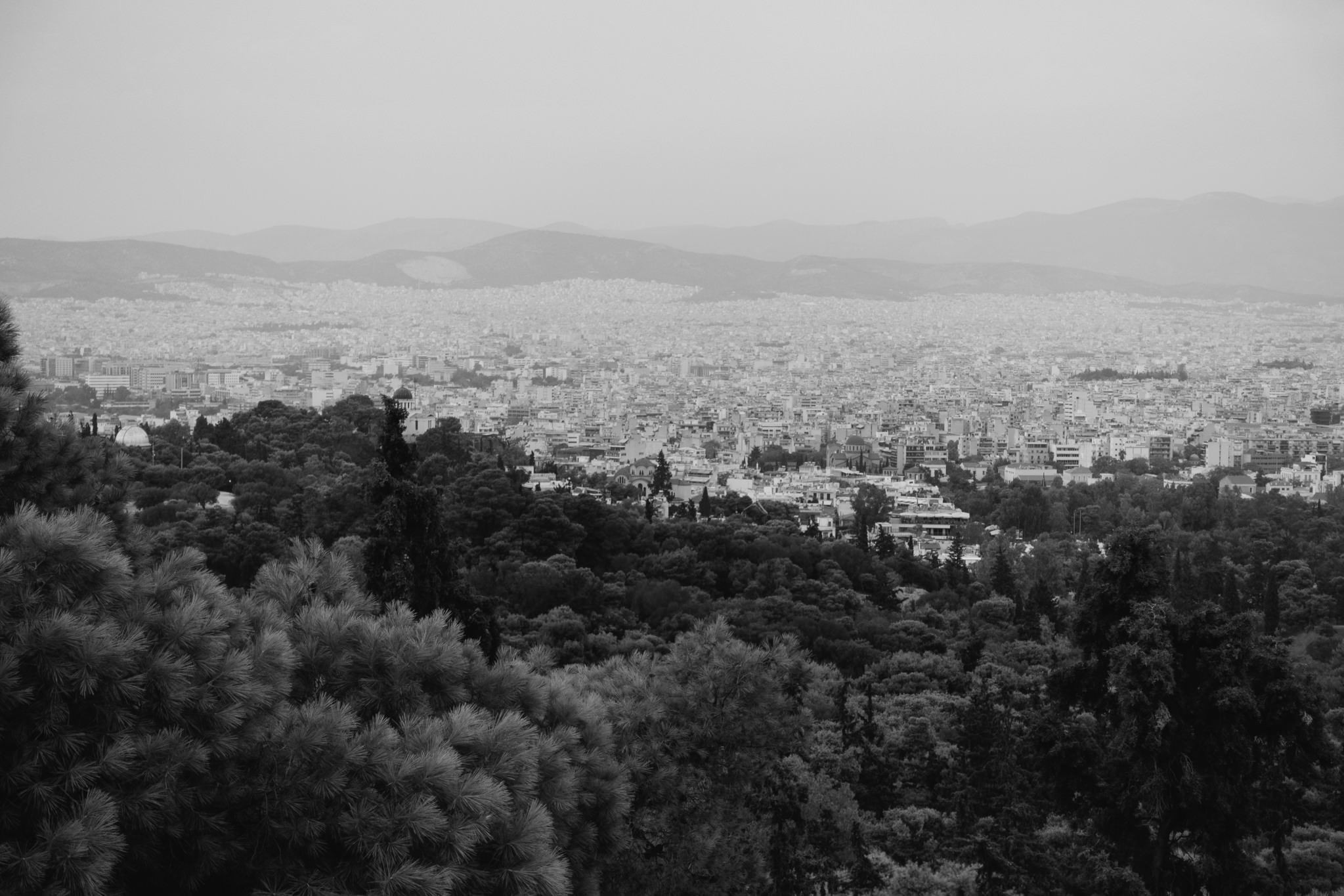 Black and white photo of Athens, Greece, viewed from a hilltop, showing the city sprawling into the distance.