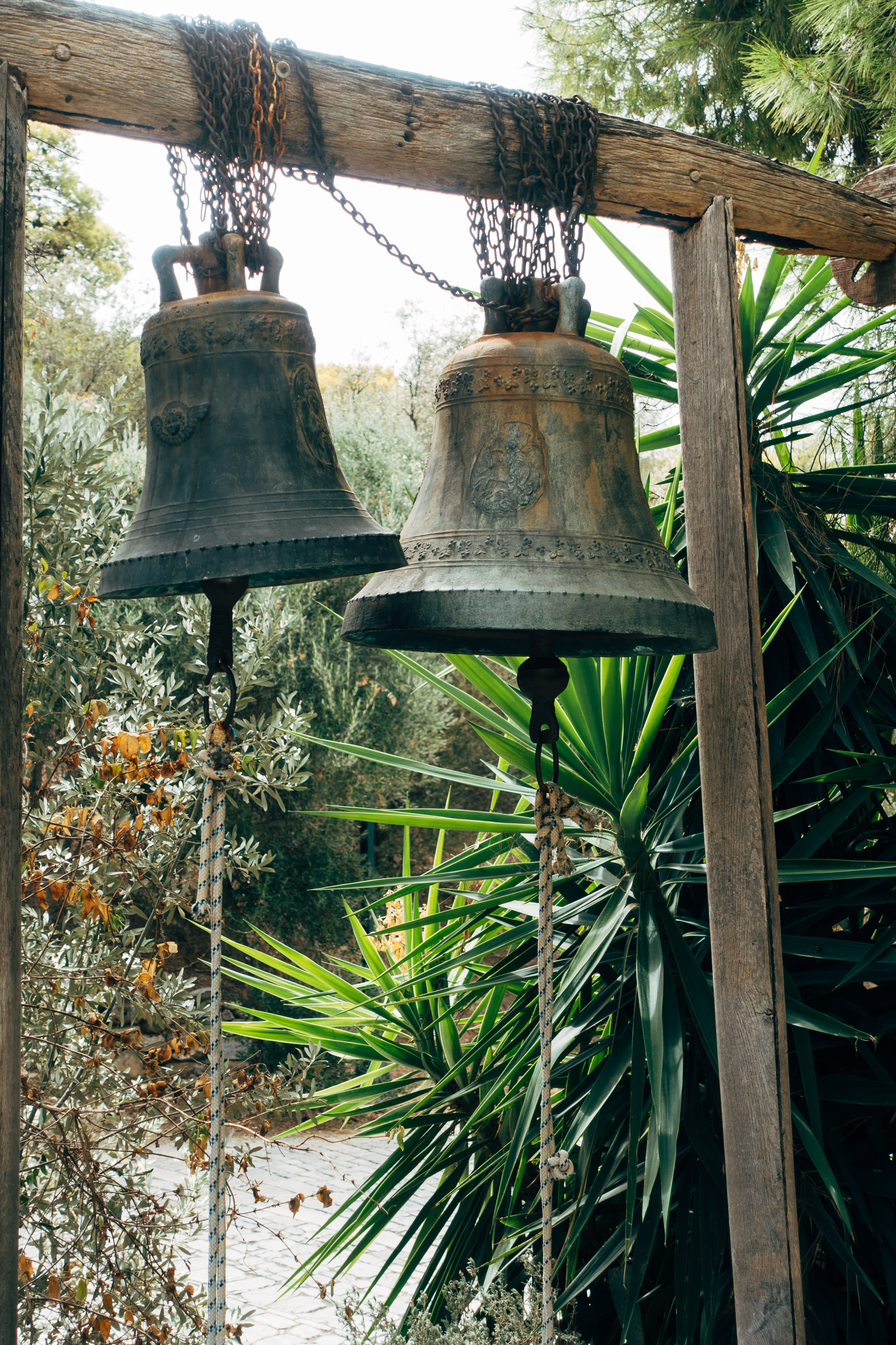 Two old bronze bells hanging from a wooden beam.