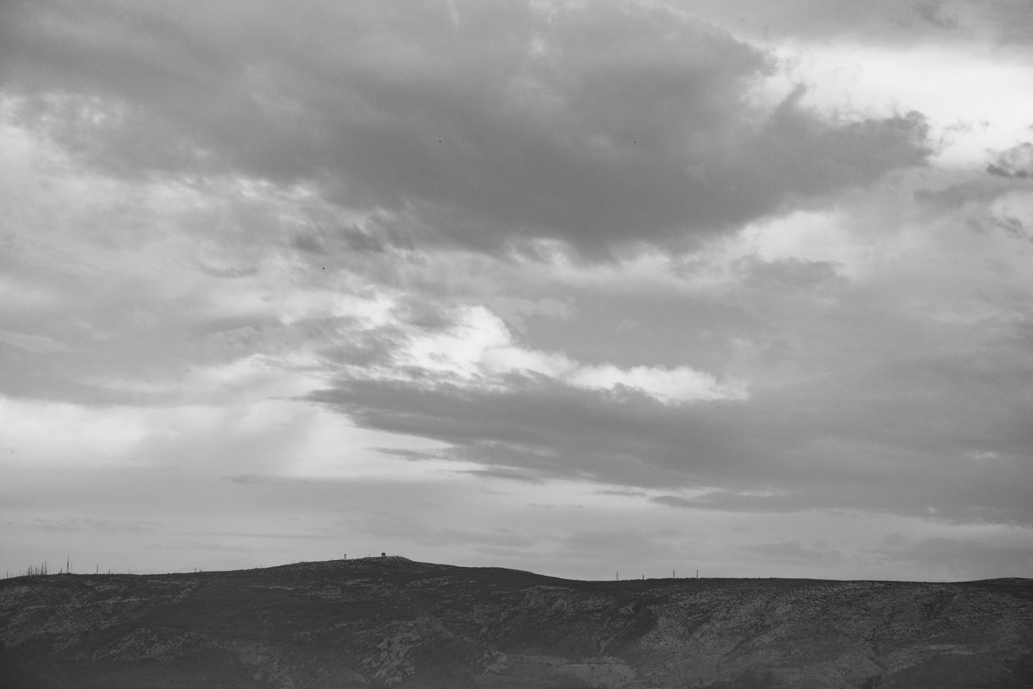 Black and white photo of Filopappou Hill in Athens, with a cloudy sky.