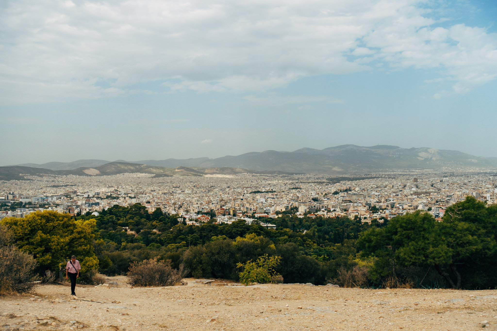 A person walks a path overlooking the city of Athens, Greece.