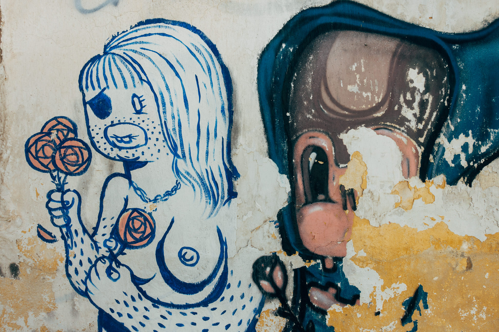 Graffiti on a weathered wall depicting a stylized woman holding roses and a partially visible figure.