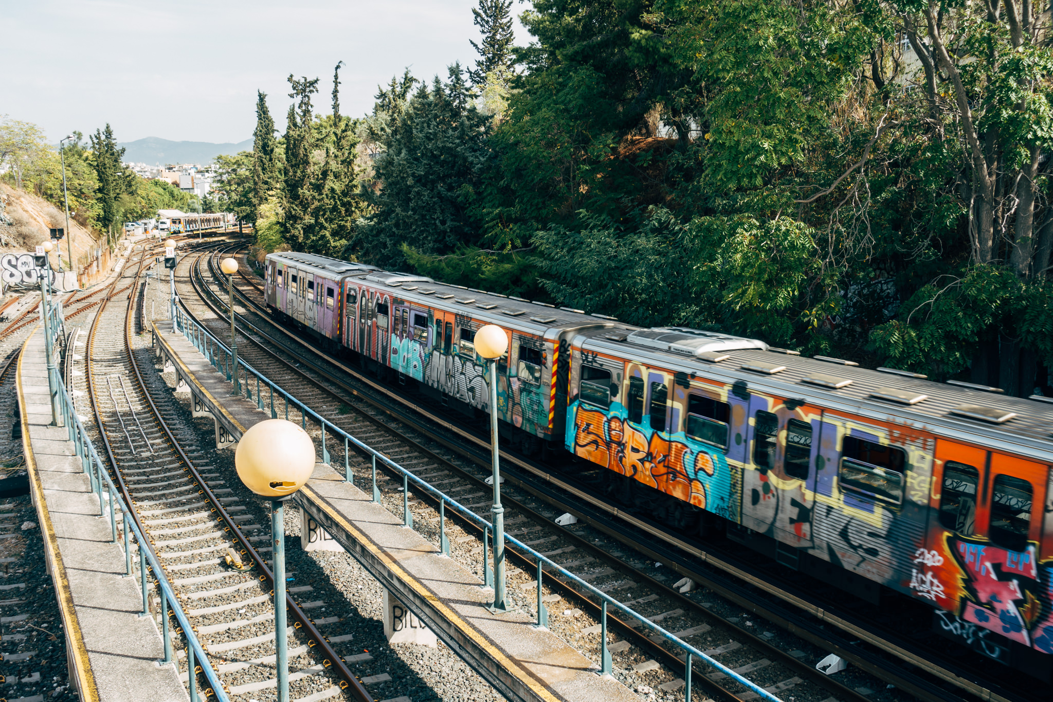 Graffiti-covered metro train moving along train tracks.