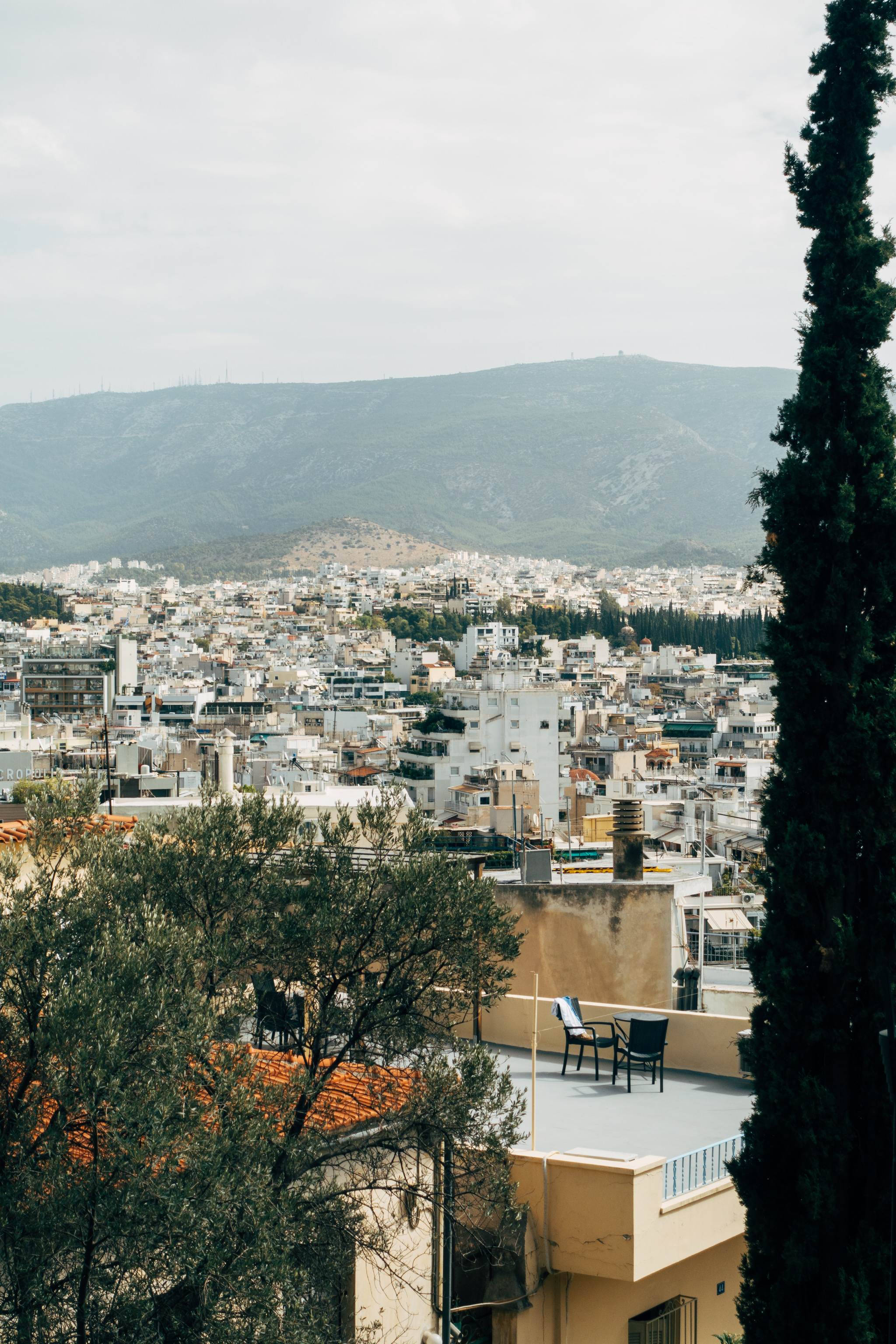 Athens cityscape with a rooftop patio and distant mountains.