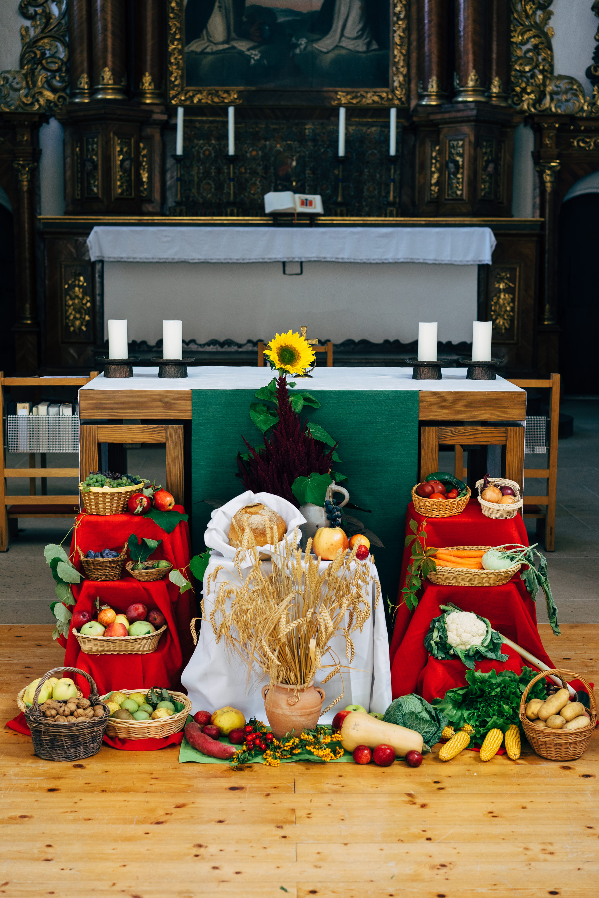 Harvest festival altar with bread, vegetables, and fruit in a church.