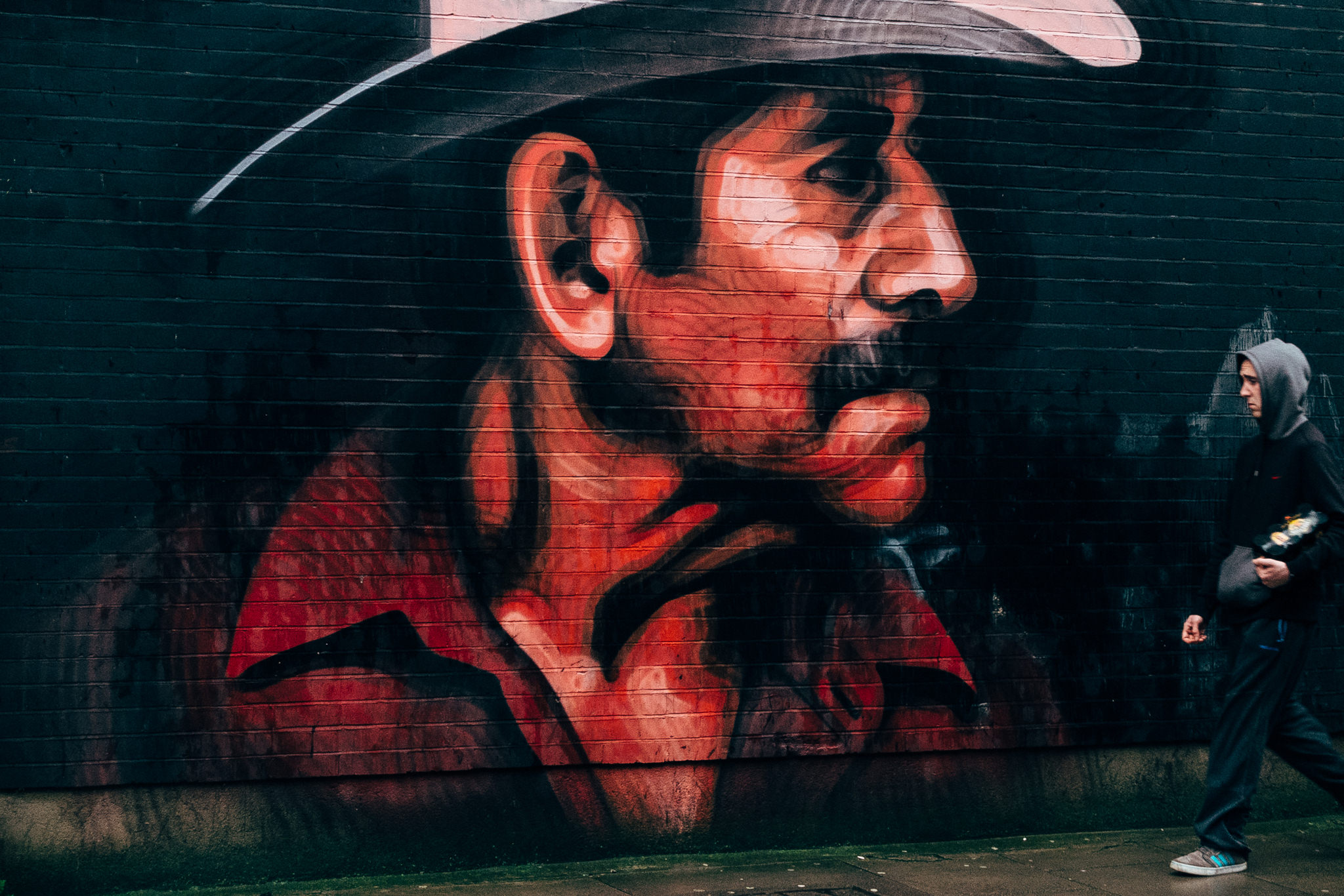 Graffiti mural of a sad cowboy's face on a brick wall.