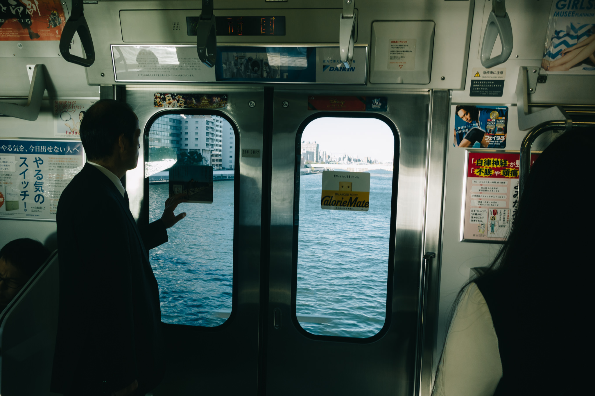 Man on train looking out window at river.