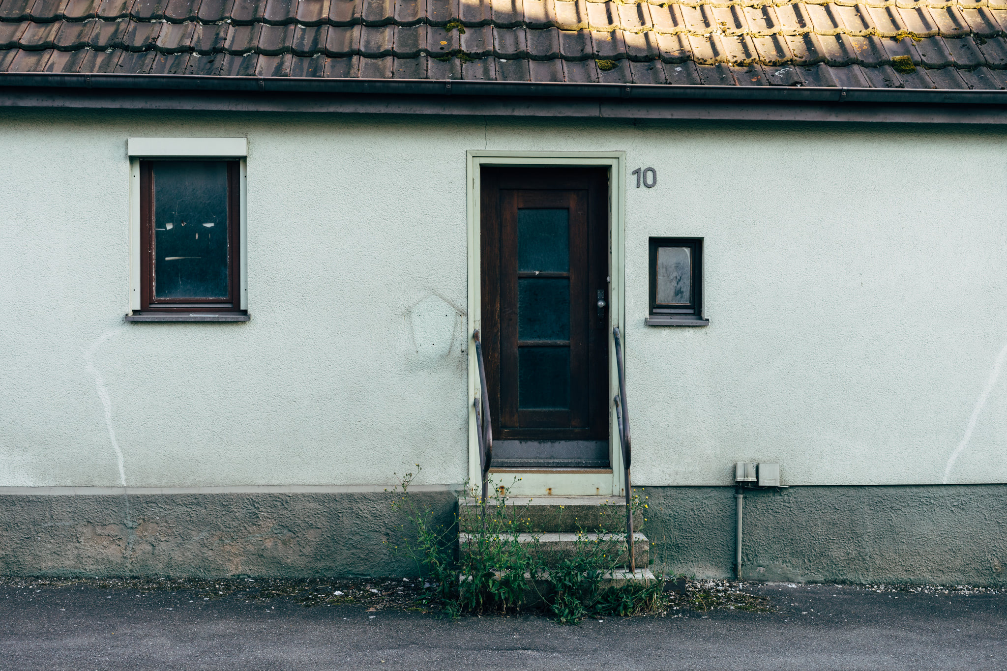 House entrance with dark wooden door, small windows, and stone steps.