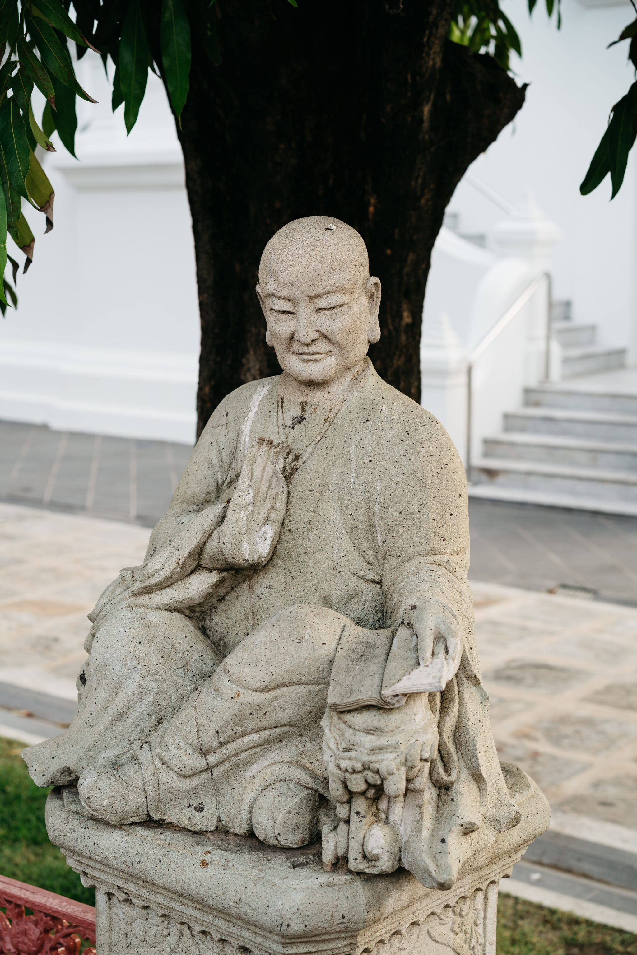 Stone statue of a seated monk at Wat Benchamabophit in Bangkok.