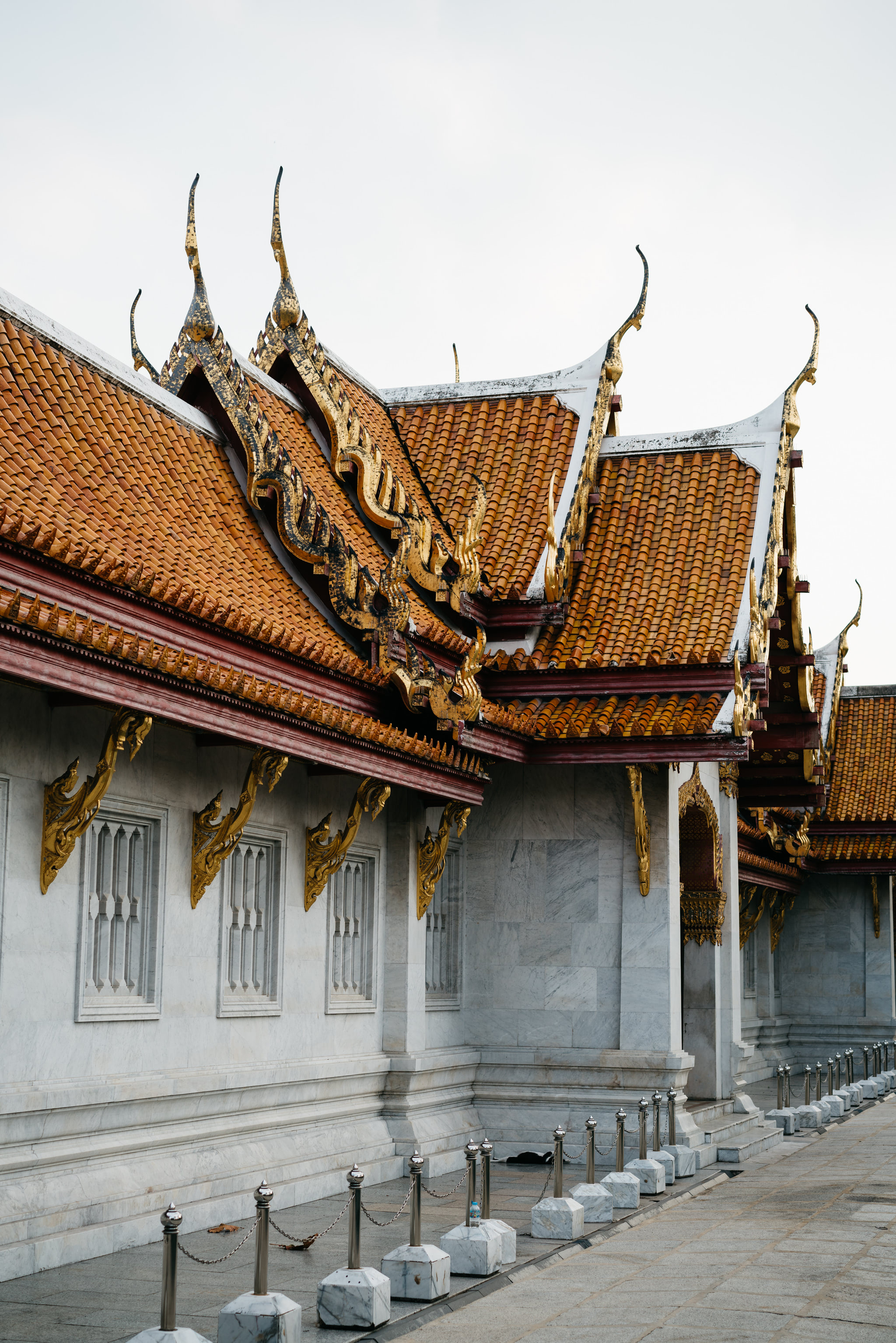 Wat Benchamabophit marble building exterior with orange roof and gold details.