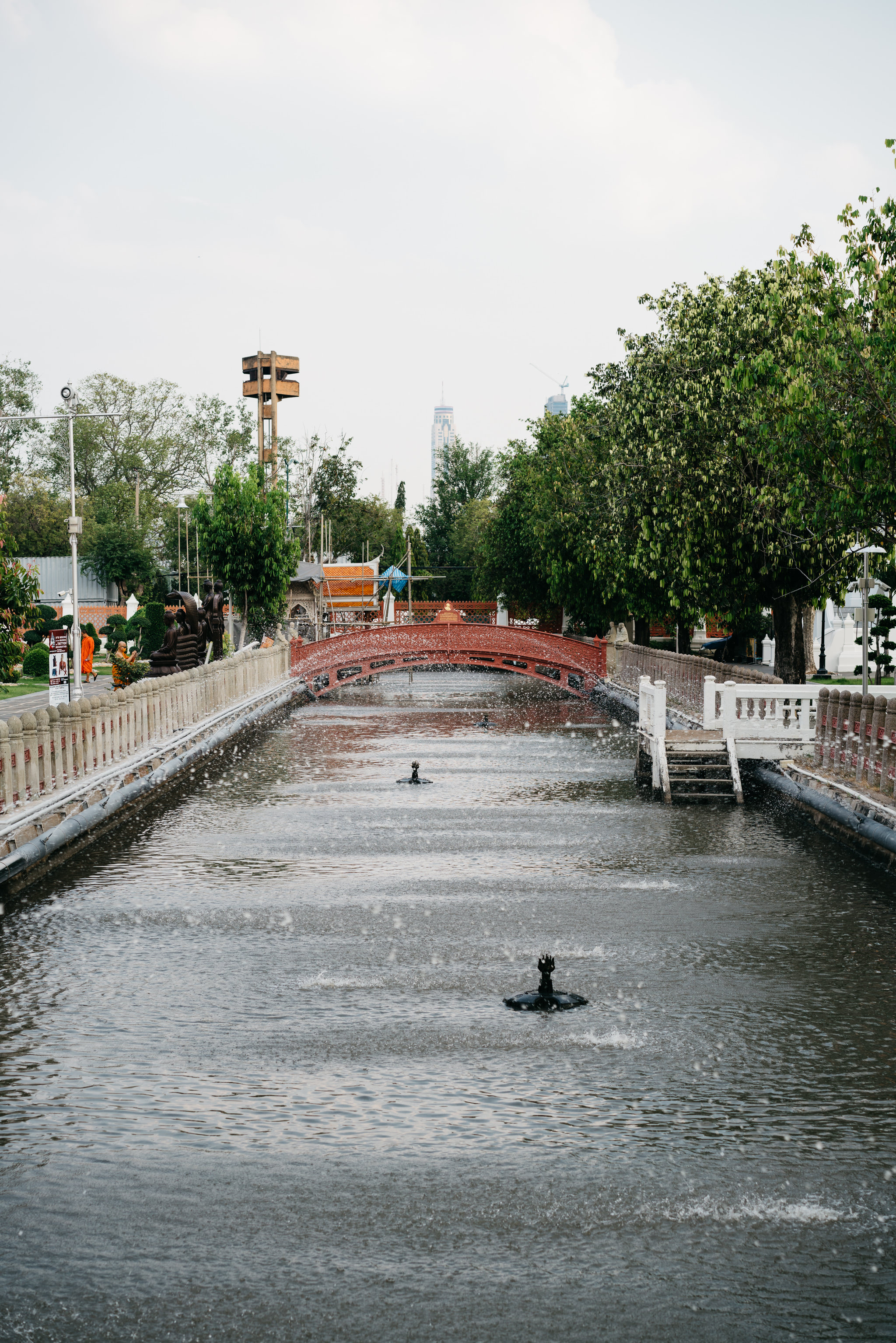 Wat Benchamabophit canal with red bridge and fountains.