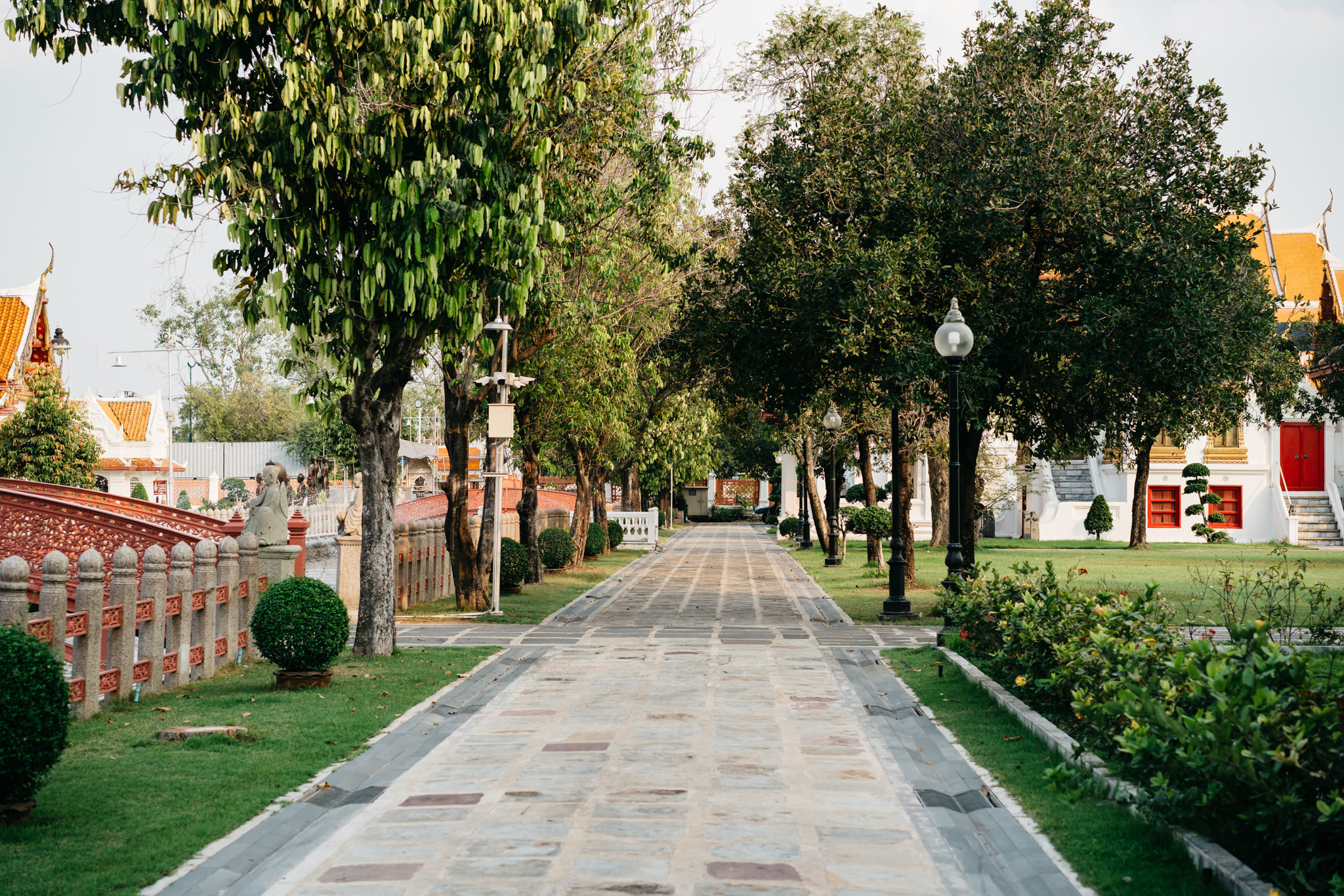 Stone pathway lined with trees leading to Wat Benchamabophit temple in Bangkok.