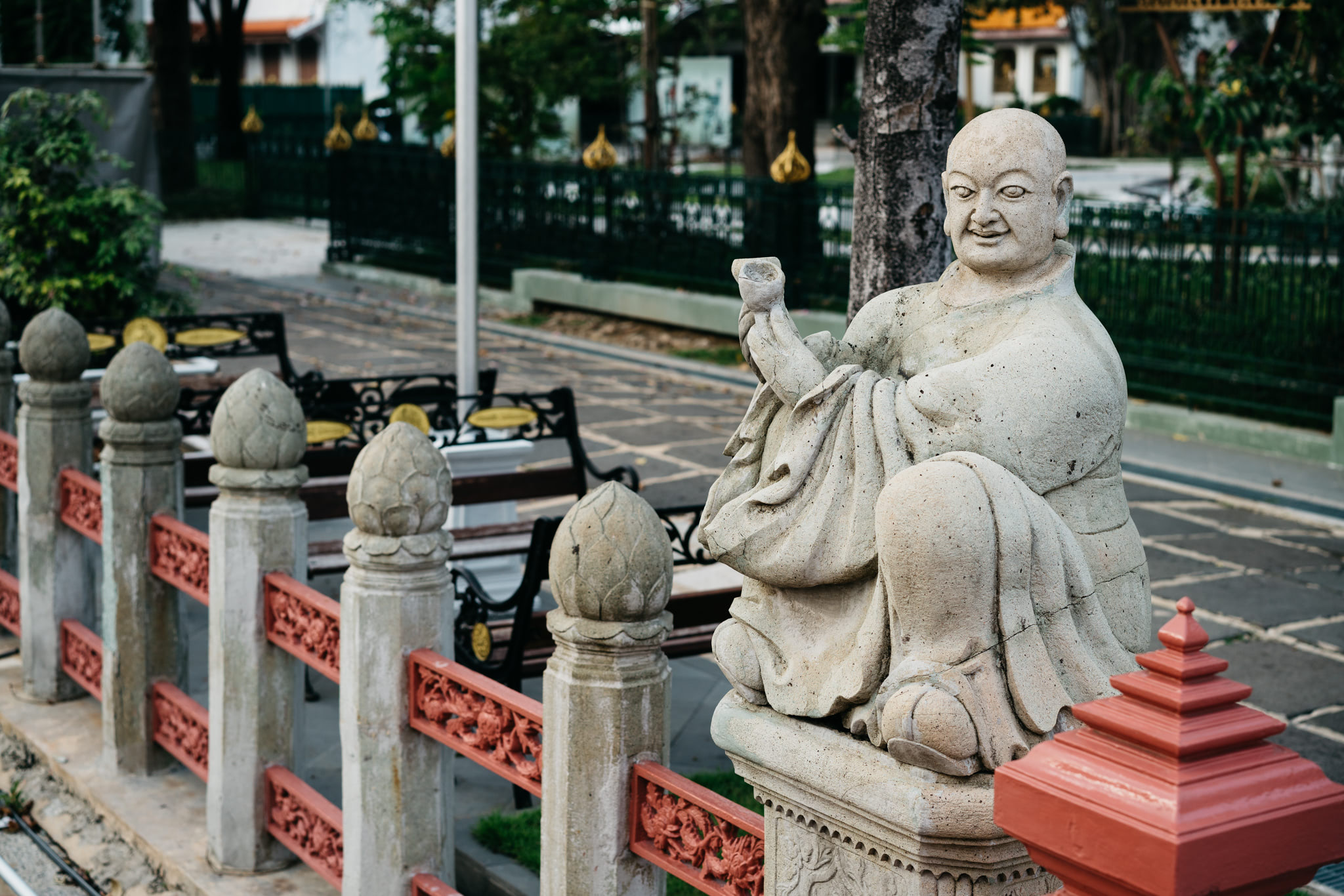 Stone statue of a smiling monk at Wat Benchamabophit in Bangkok.