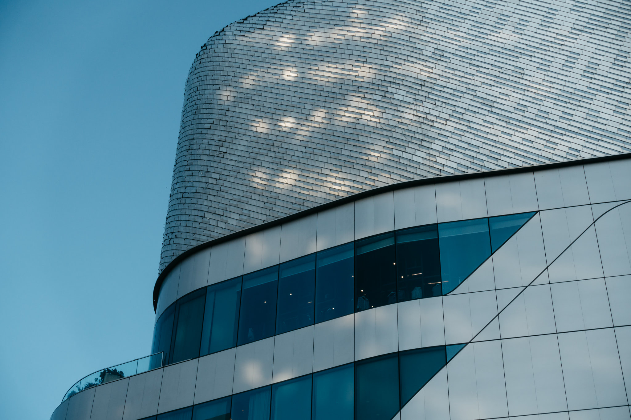 Modern Bangkok building with blue glass windows and textured silver facade.
