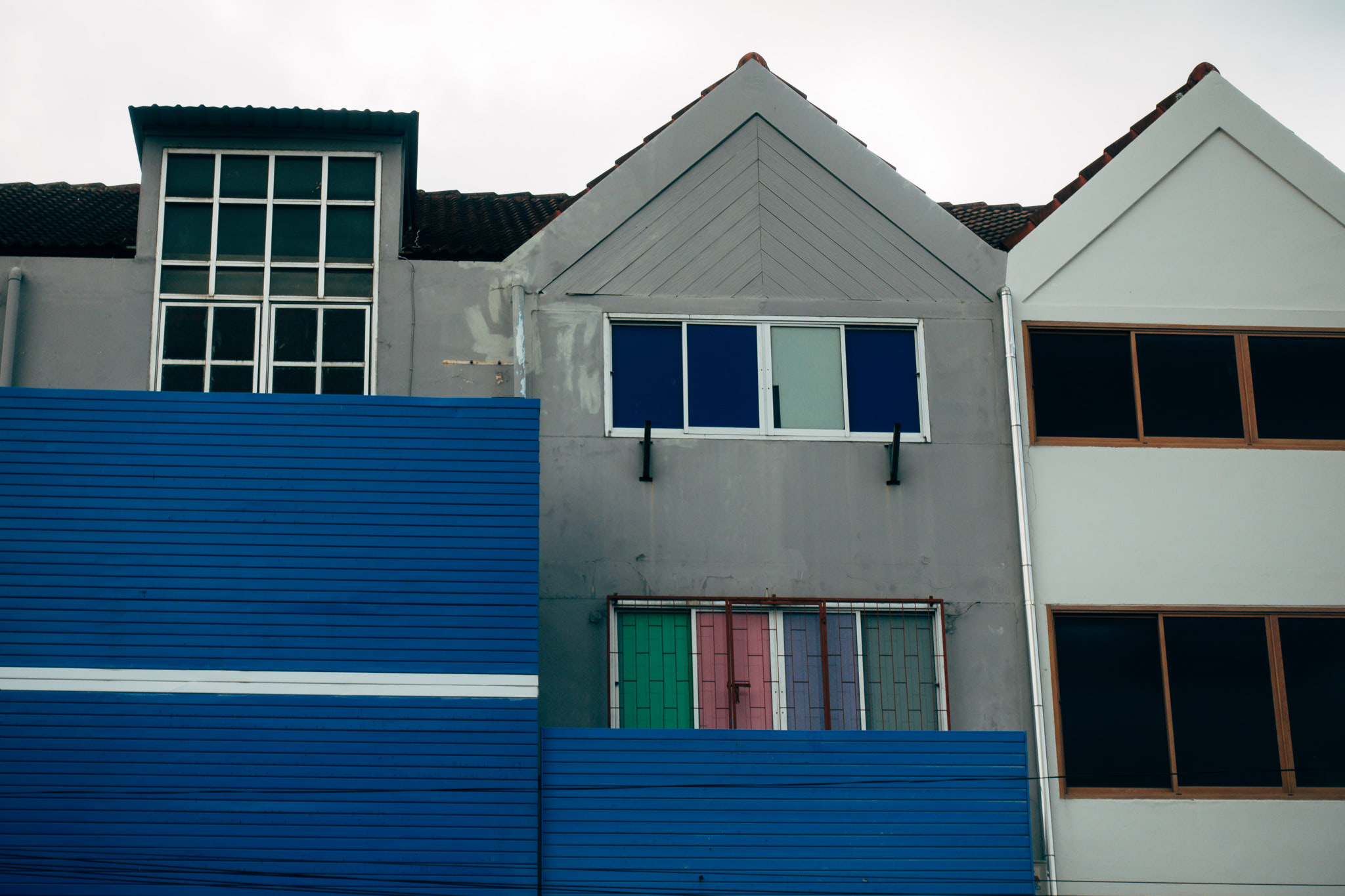Three-story building with blue, gray, and white walls; multi-paned windows; and colorful doors.