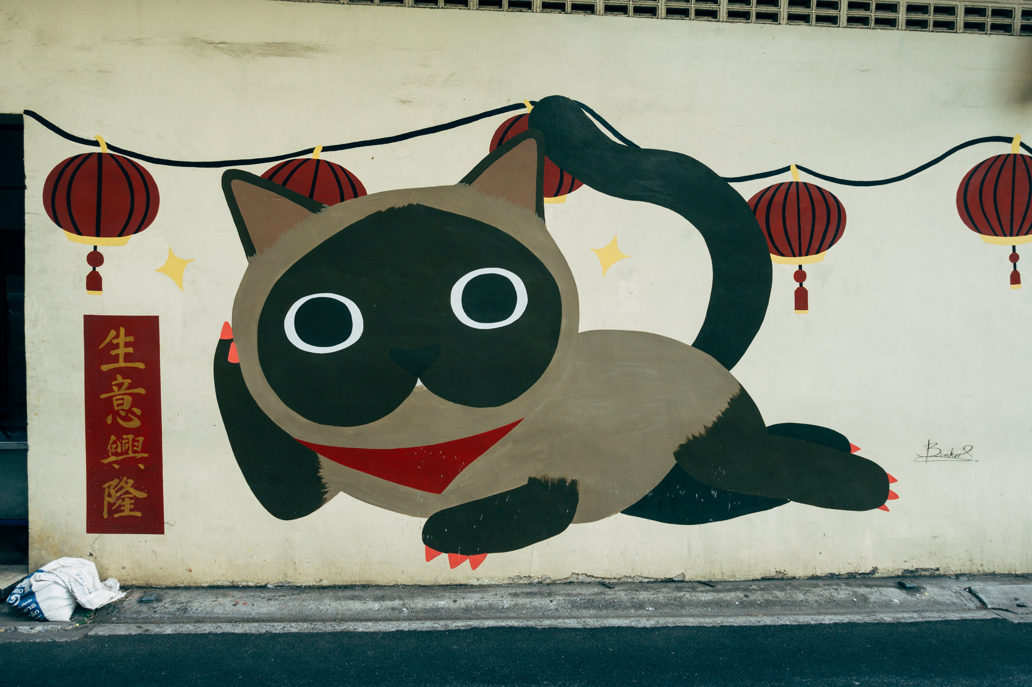 Mural of a cartoon Siamese cat with red lanterns.