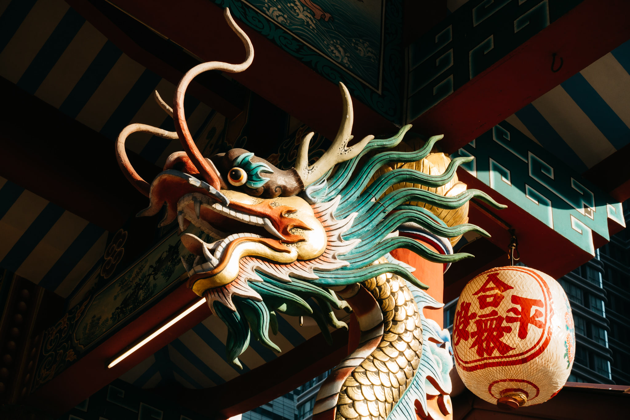 Close-up of a colorful carved dragon on a Chinese temple, with a lantern visible.