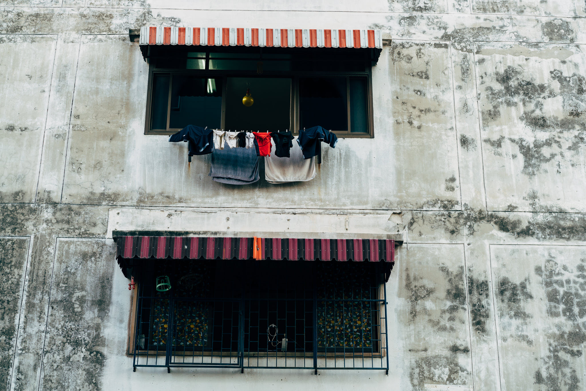 Laundry hanging from a window on a weathered building.