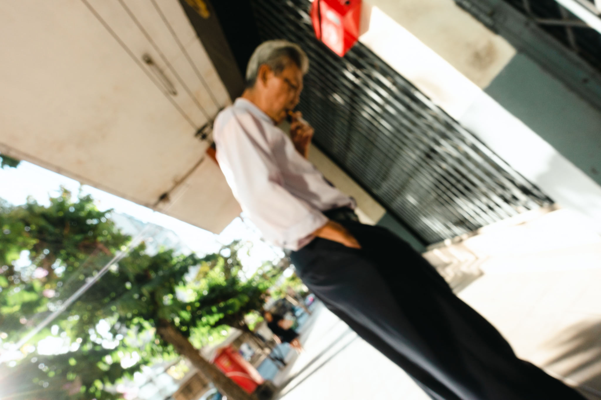 Blurry photo of a man smoking on a city street.