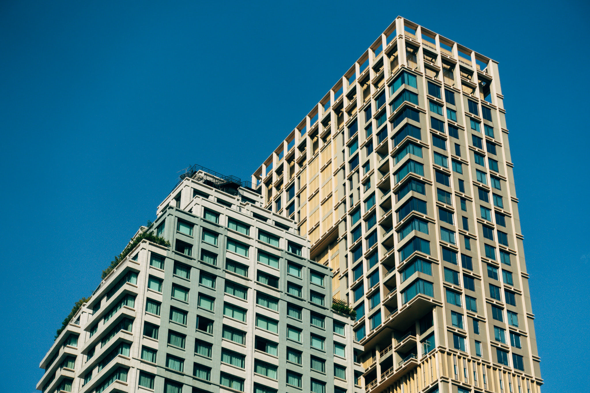Two modern high-rise buildings against a clear blue sky.
