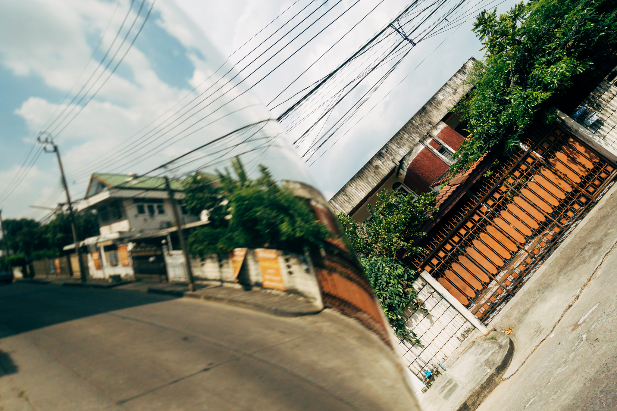 Distorted street view reflected in a mirror, showing houses and power lines.