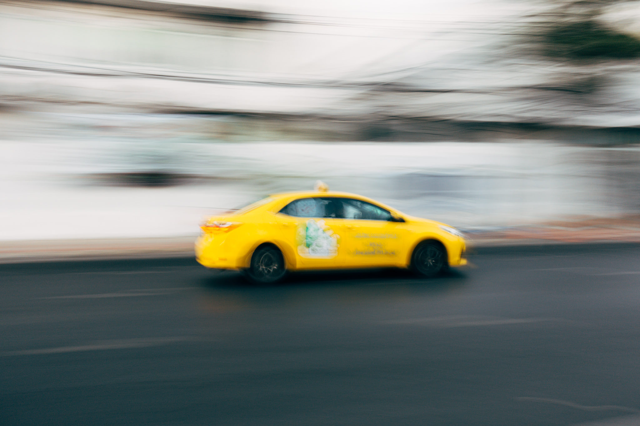Blurred photo of a yellow taxi speeding down a street.