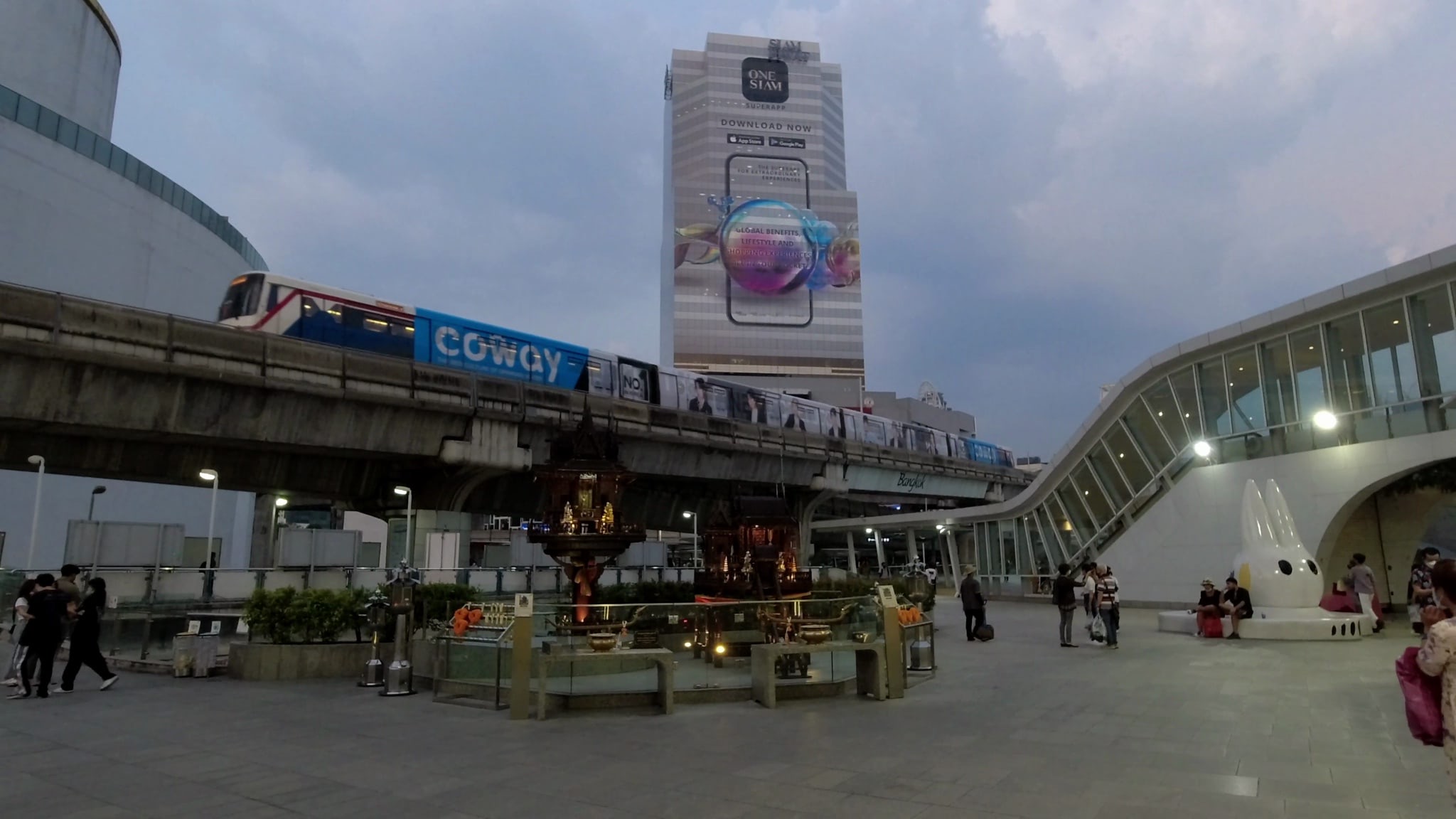 Bangkok street scene with elevated train and shrine.