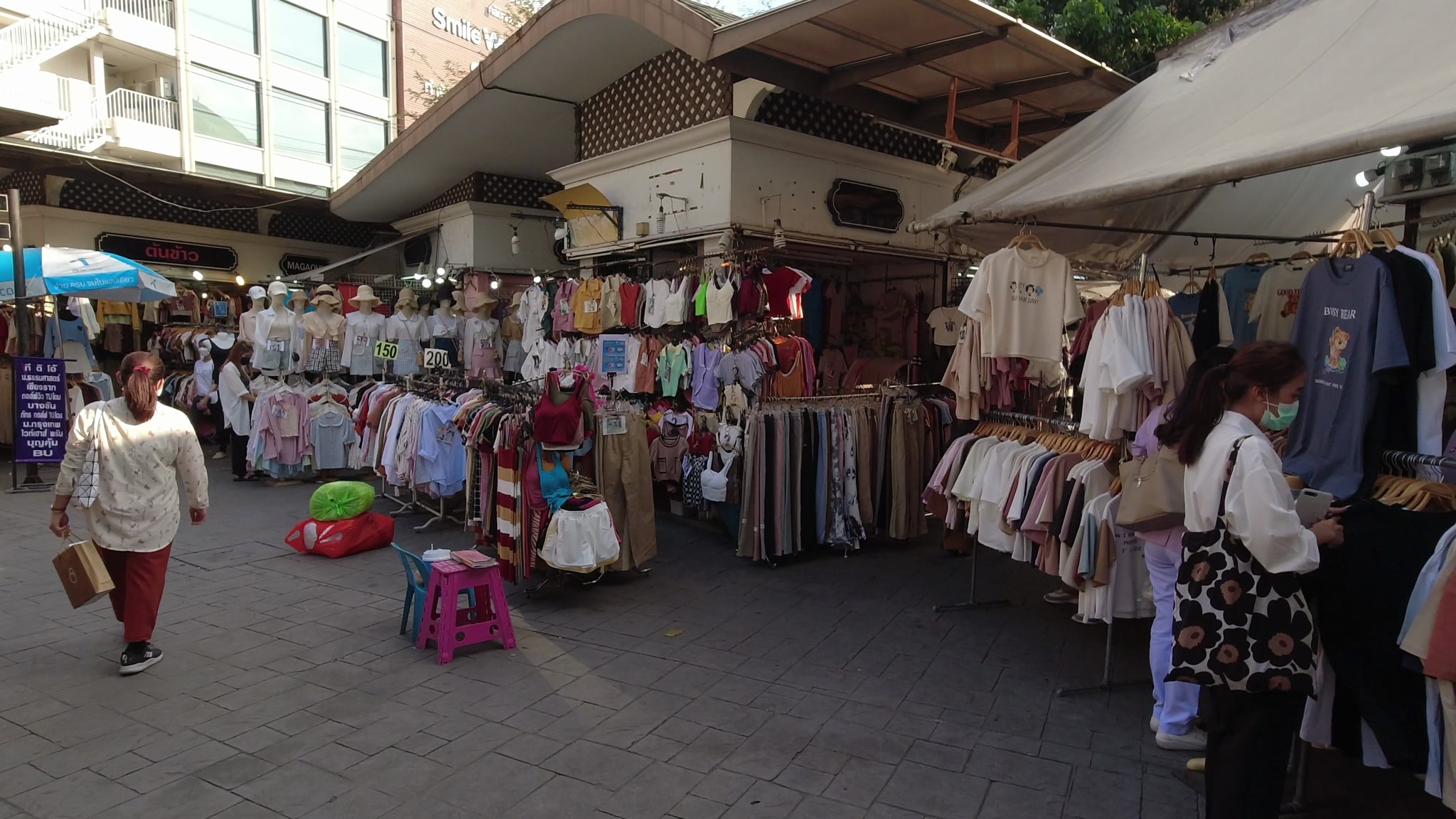 Bangkok clothing market with various shops and clothing racks.