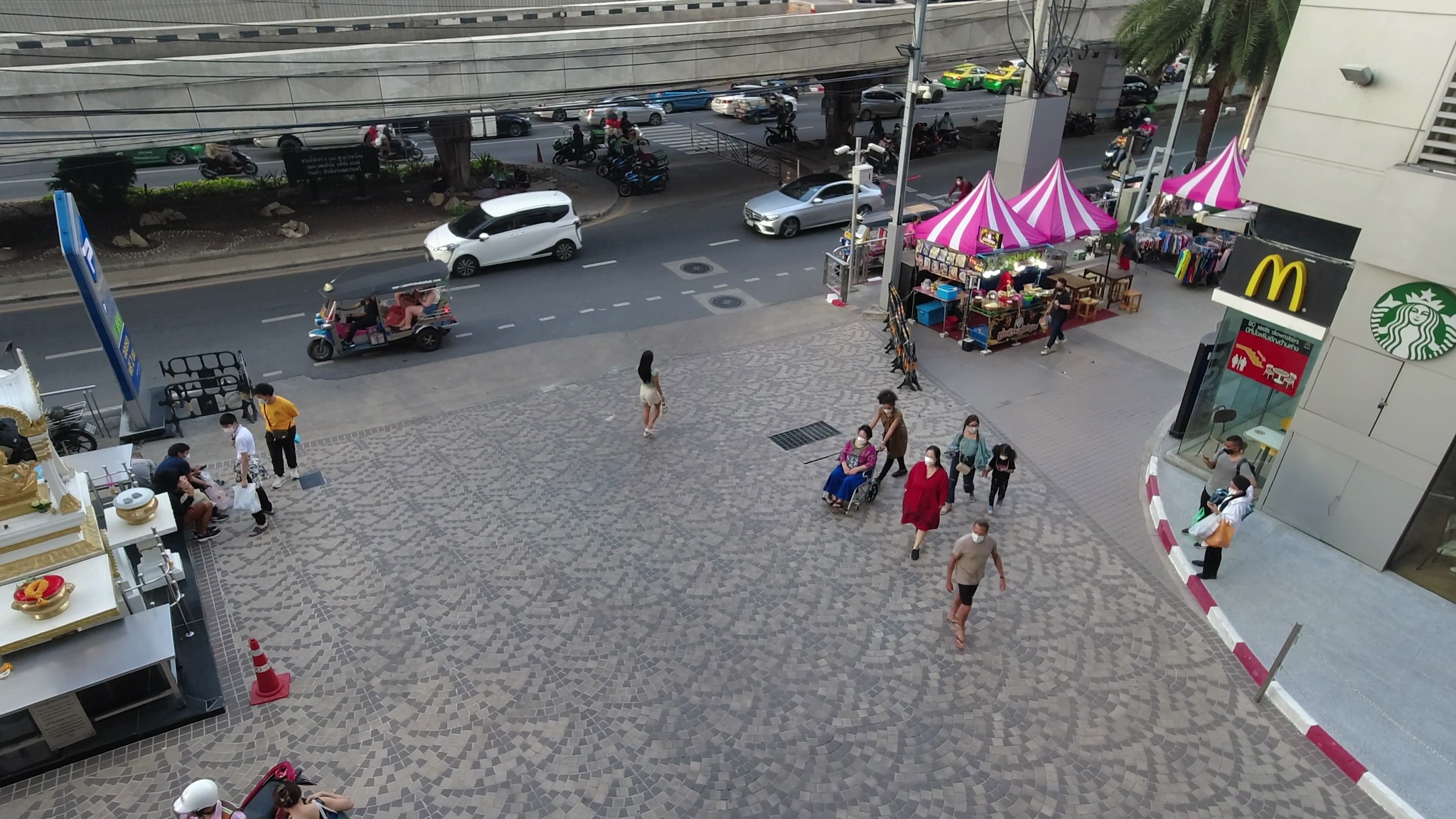 Aerial view of a city street scene with pedestrians, vehicles, and street vendors.