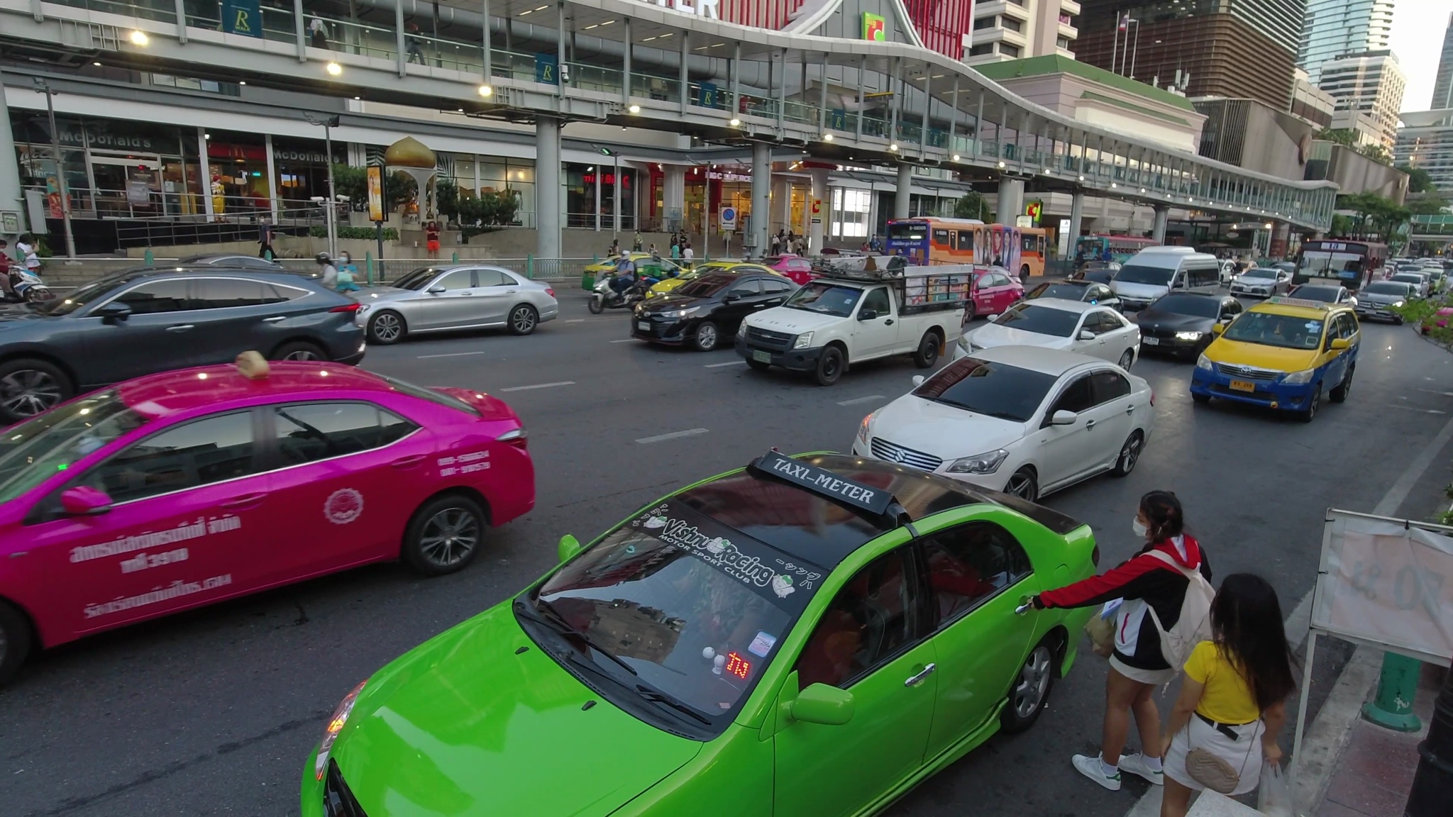 Bangkok street scene with traffic and a bright green taxi.