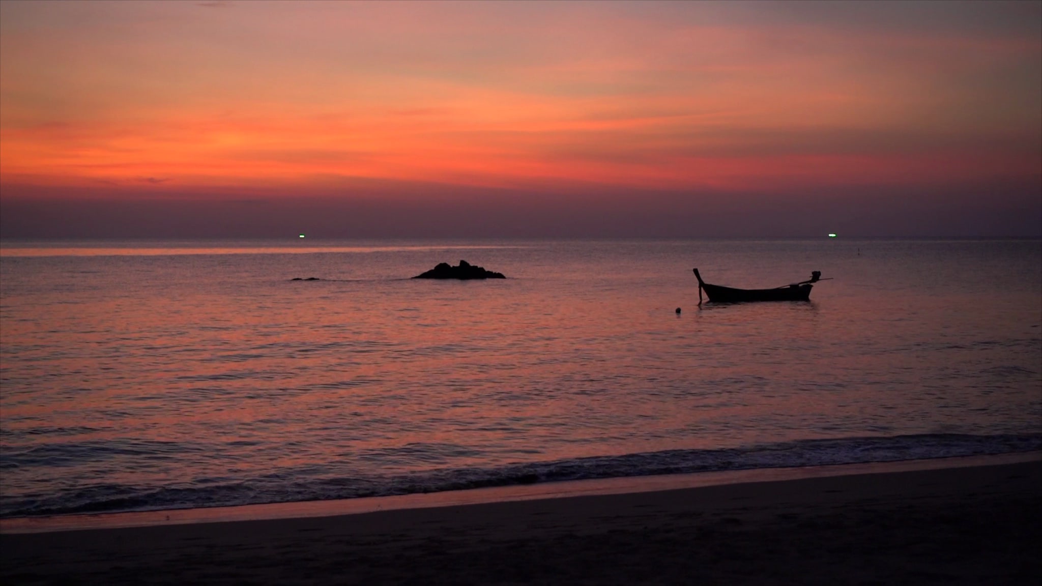 Sunset over ocean with longtail boat.