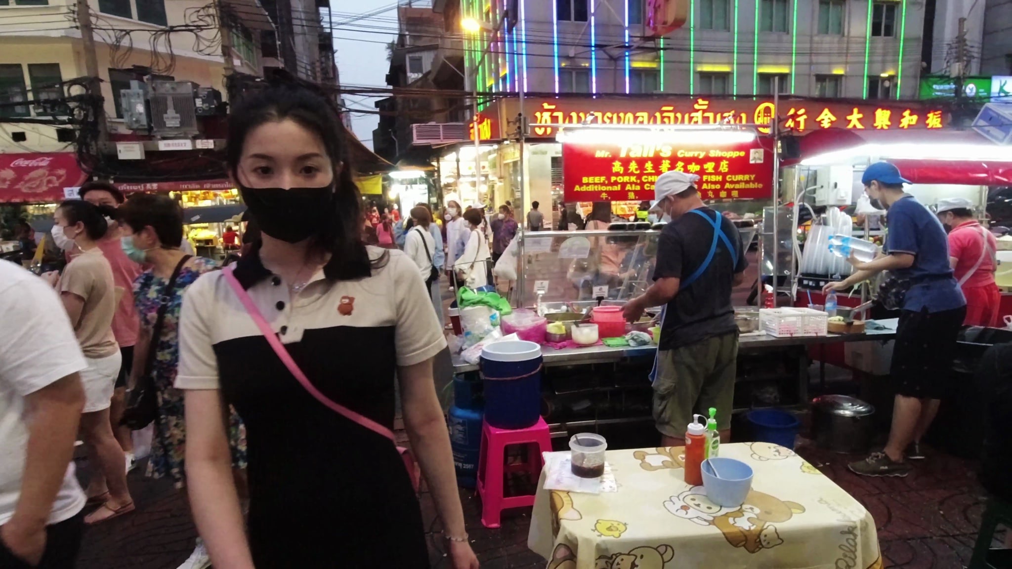Woman wearing a face mask in Bangkok's Chinatown, near food stalls.