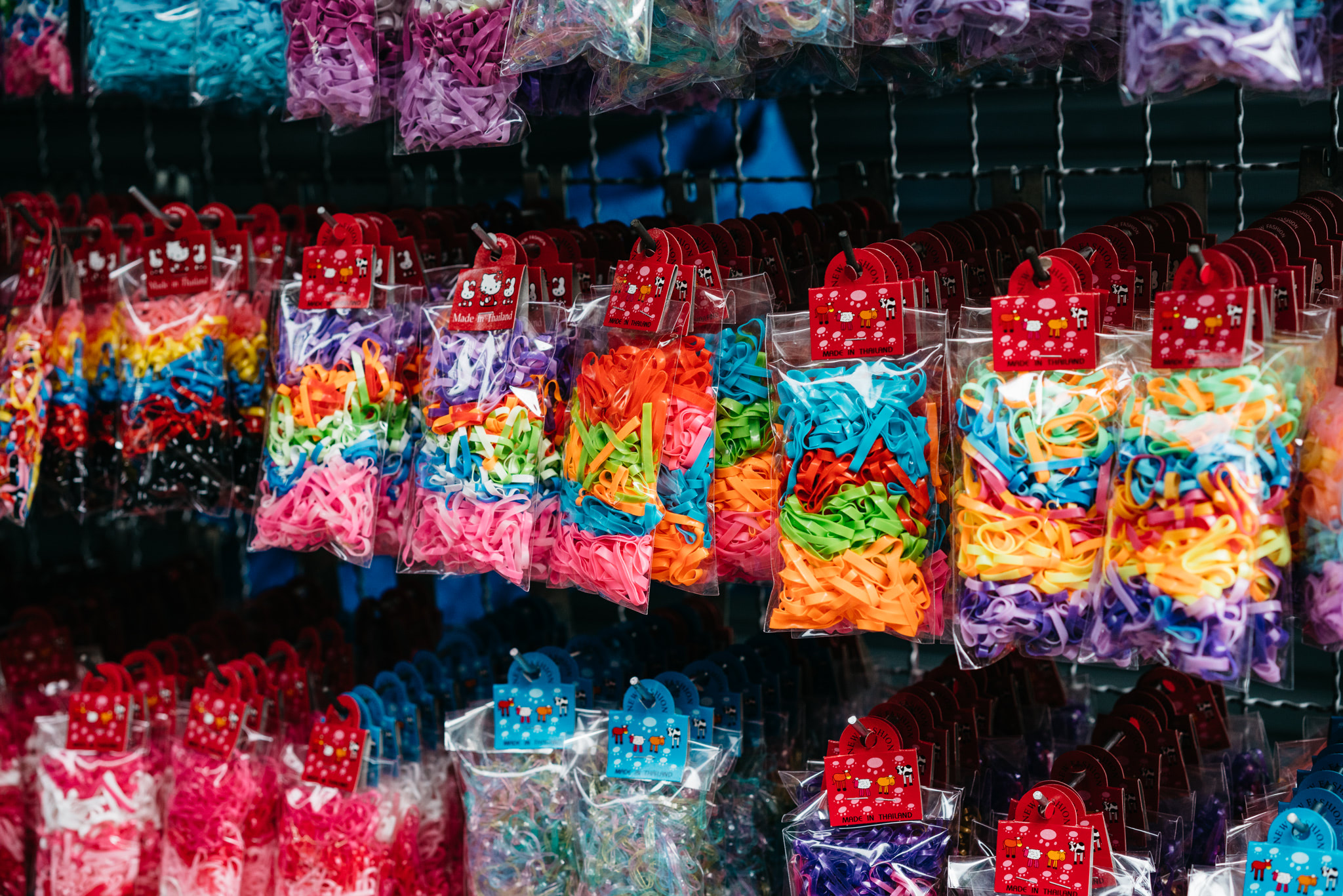 Many bags of colorful hair ties hanging on a rack.