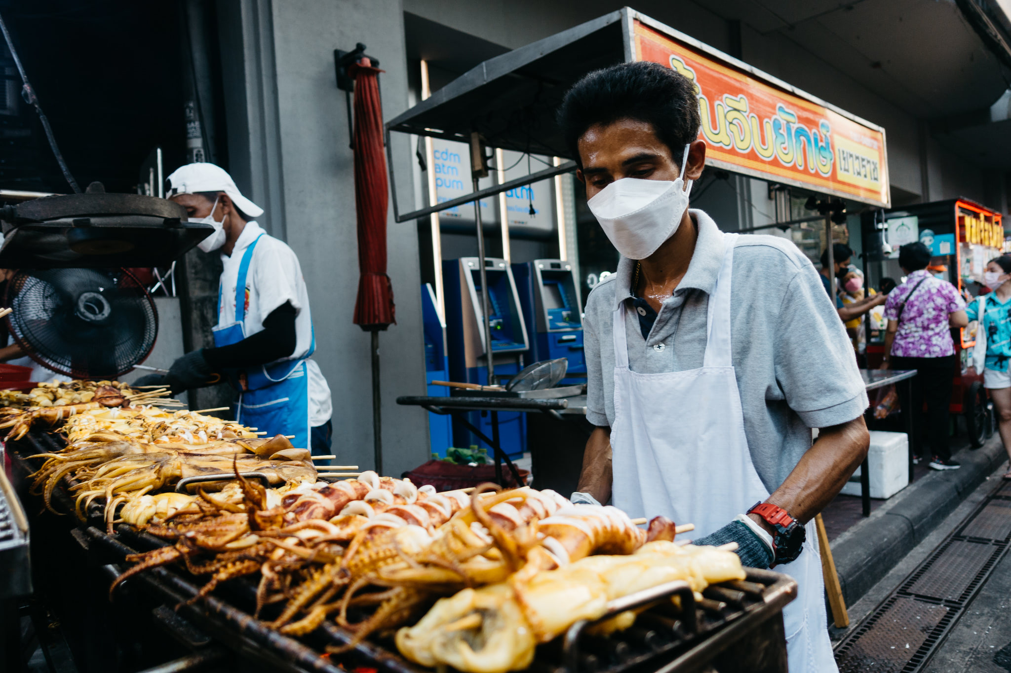 Bangkok Chinatown street food vendor grilling seafood on skewers.