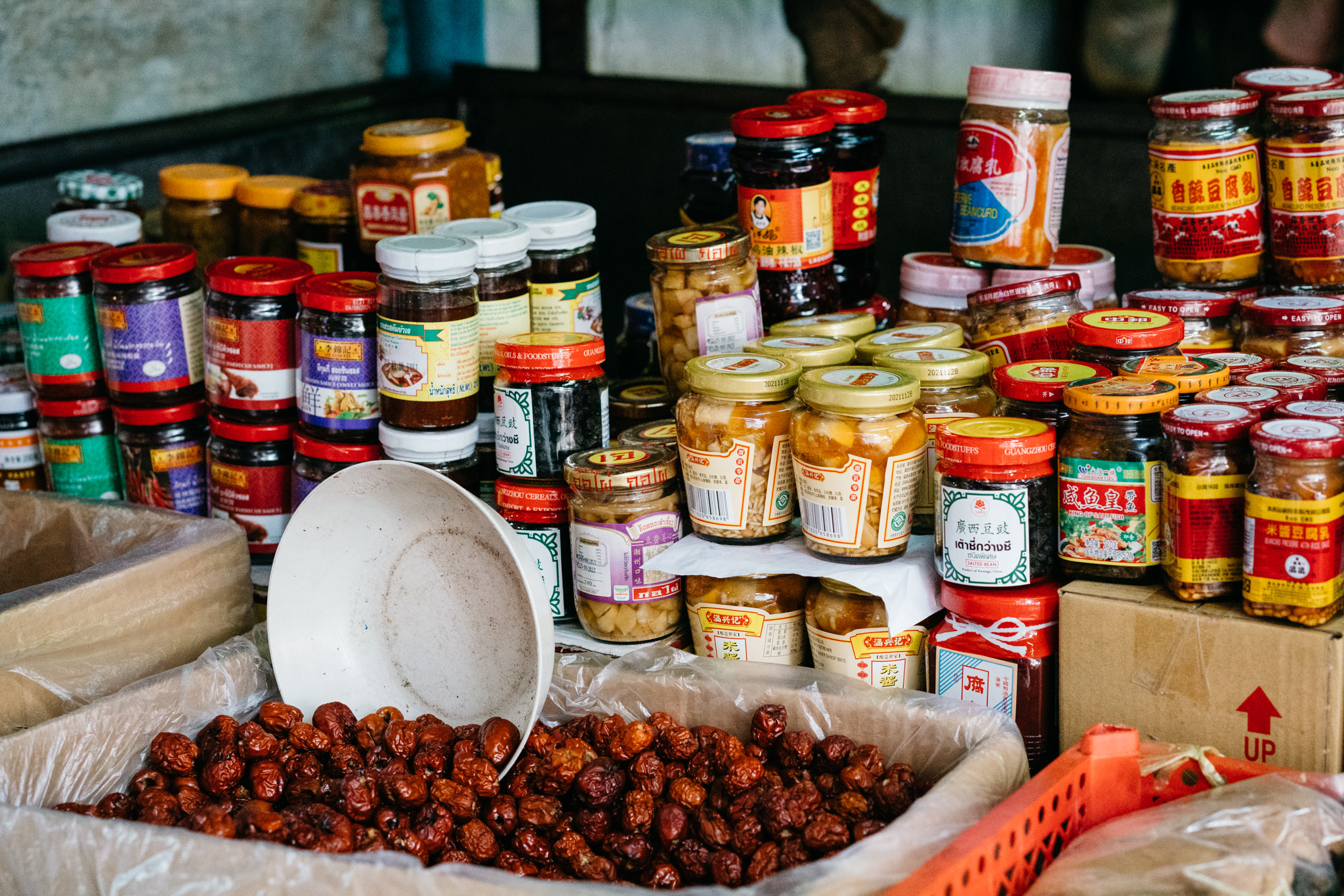 Assortment of jars of preserved food and dried jujubes in Bangkok Chinatown shop.