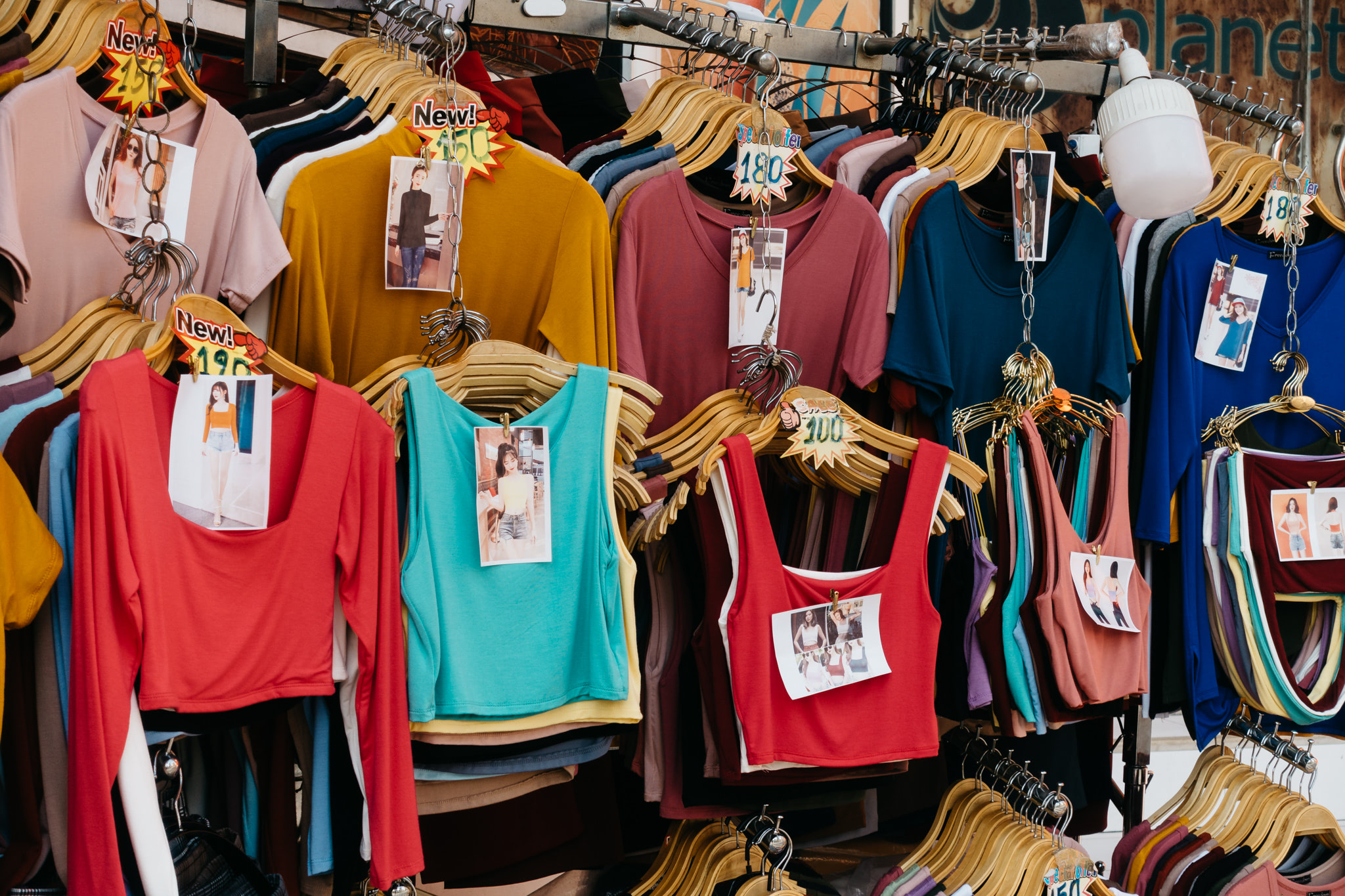 Rack of colorful women's tops and tank tops for sale.