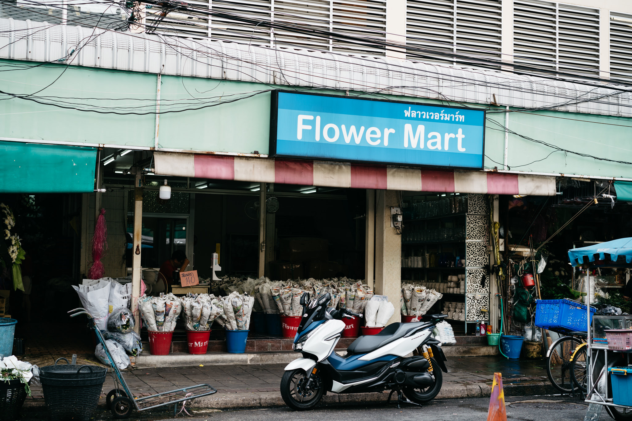 Bangkok flower market with a scooter parked outside.