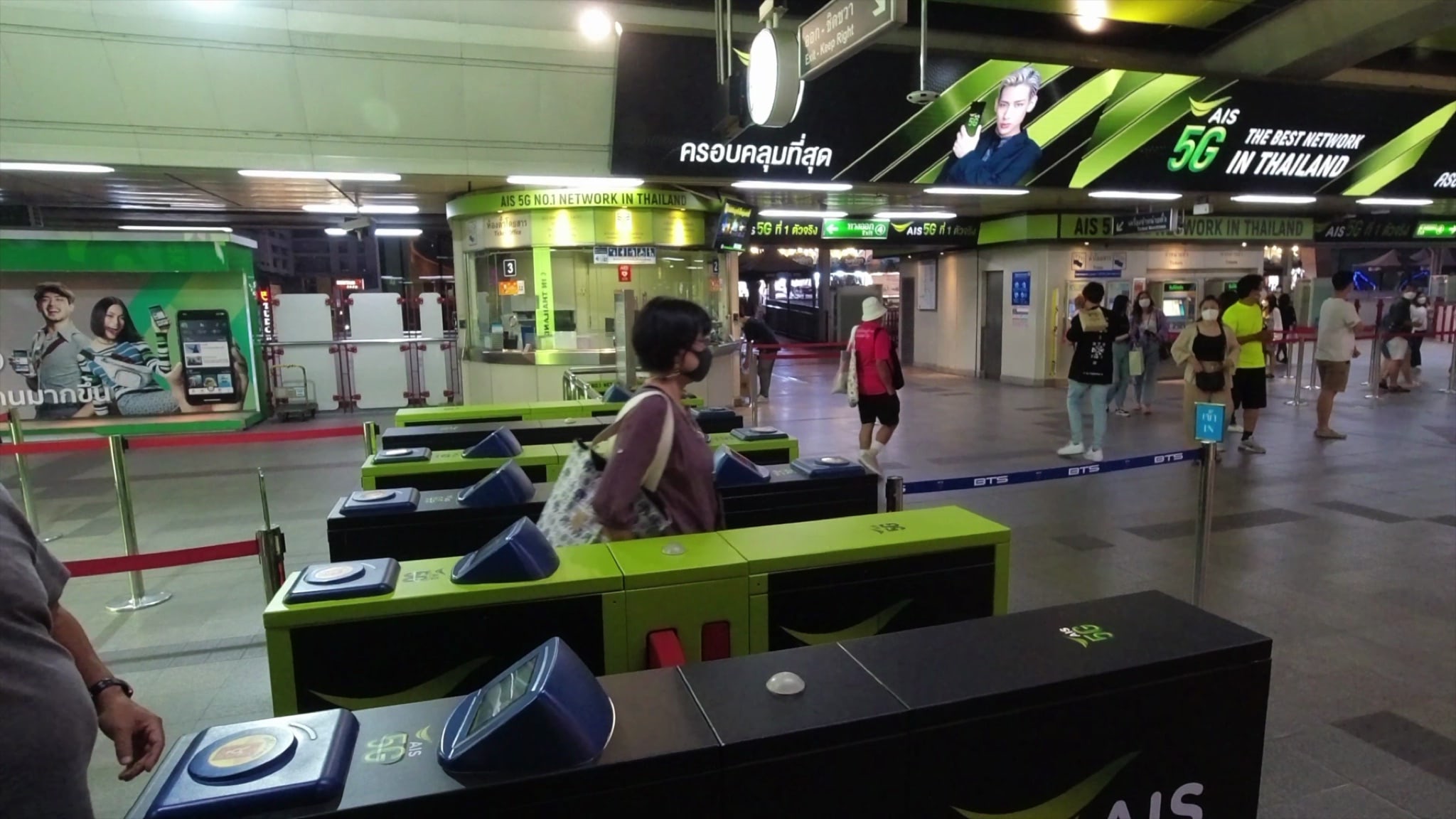 People passing through turnstiles at a transit station.