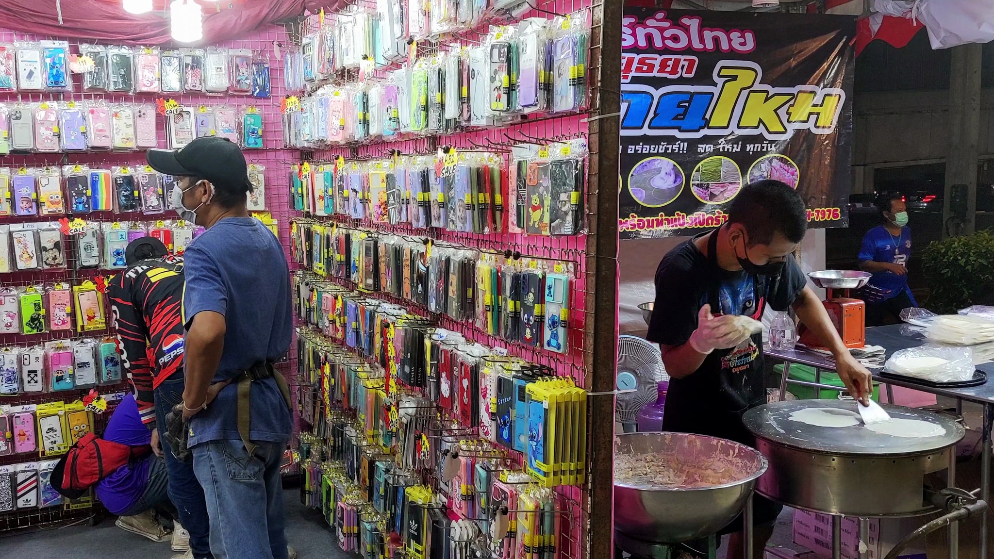 Bangkok street market selling phone cases and making crepes.