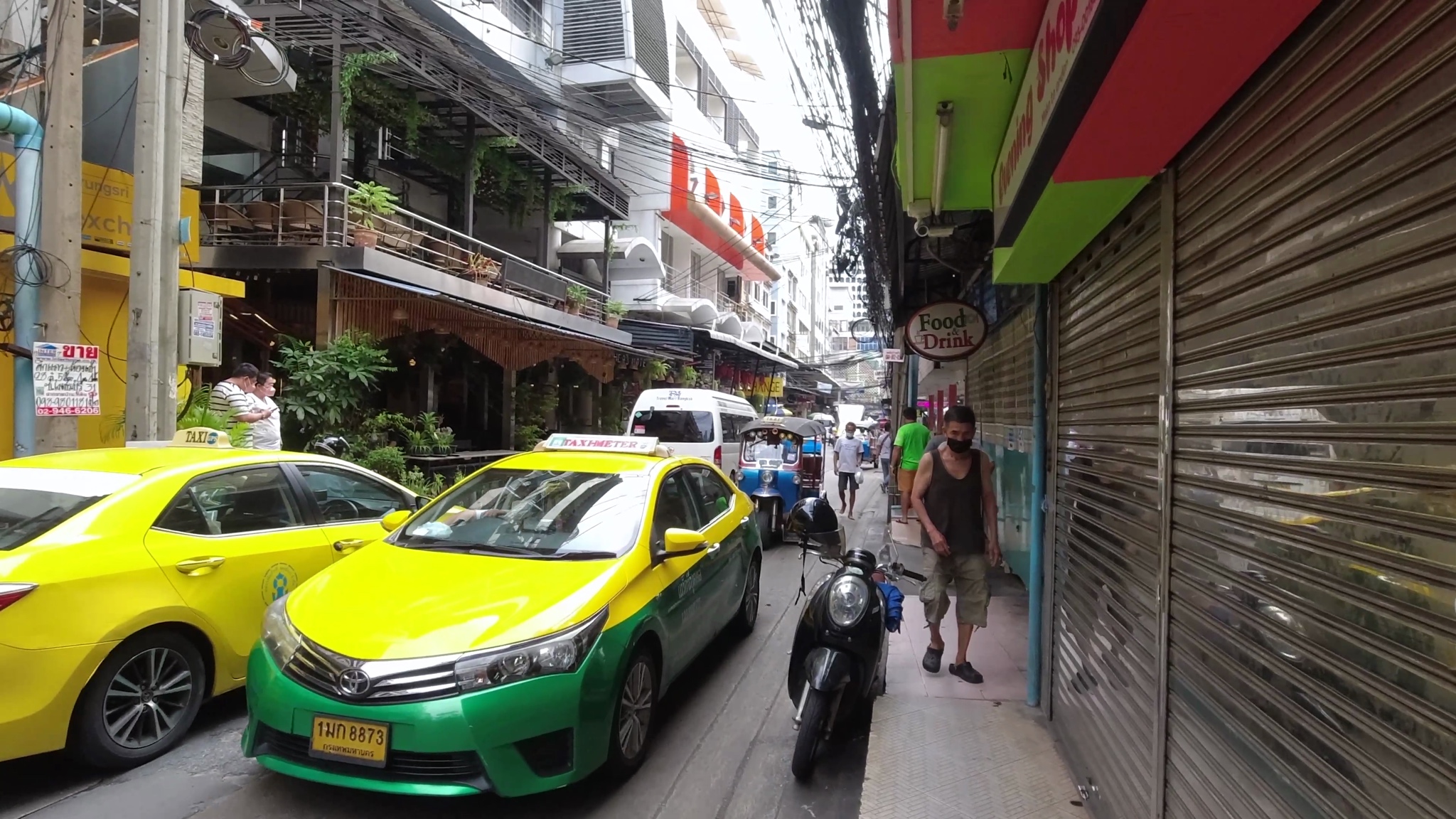 Bangkok street scene with taxis, tuk-tuk, and pedestrians.