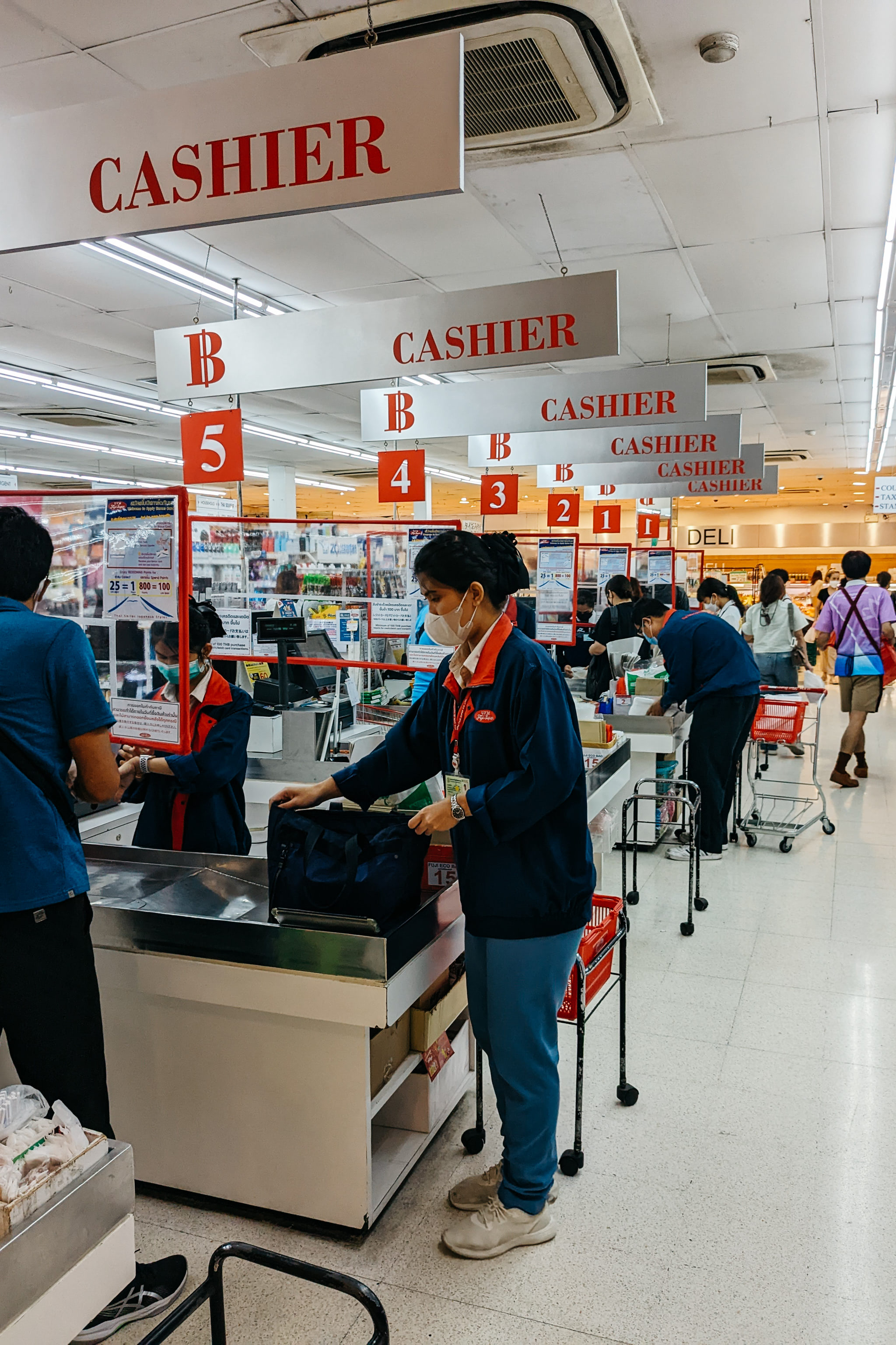 Cashiers at a Bangkok Japanese supermarket, customers checking out.