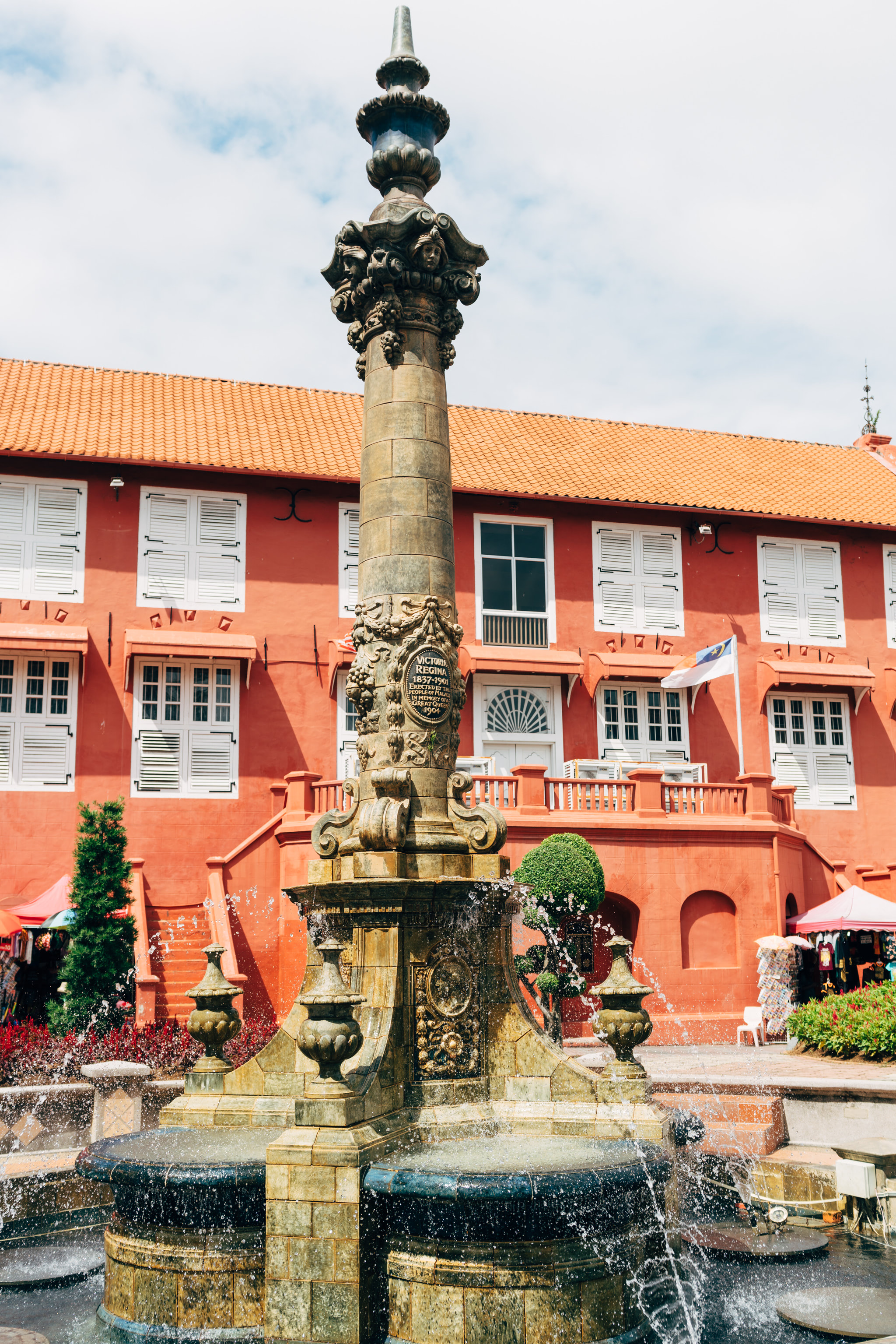 Ornate fountain in front of a red building.