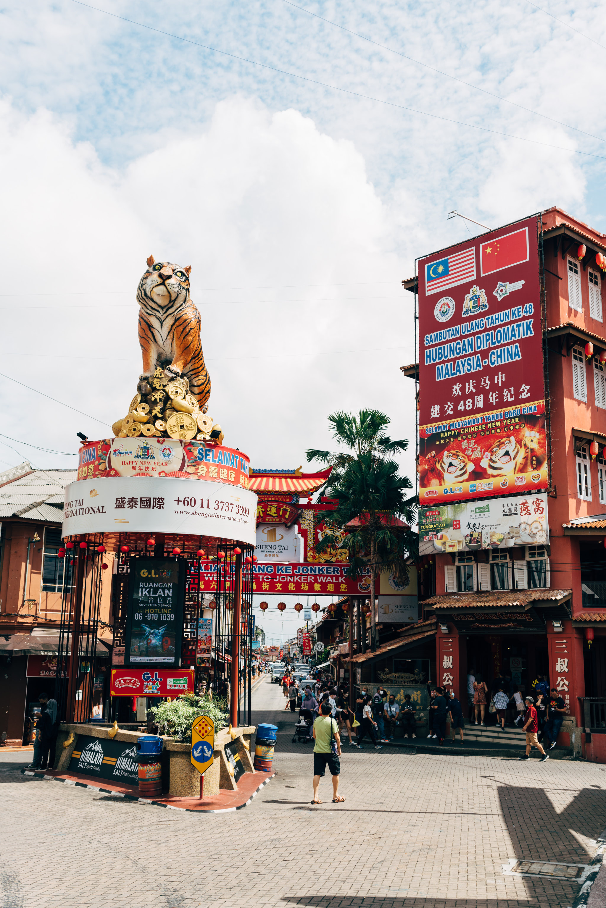 A large tiger statue sits atop a pile of gold coins in Malacca, Malaysia, in front of a Chinese New Year celebration.