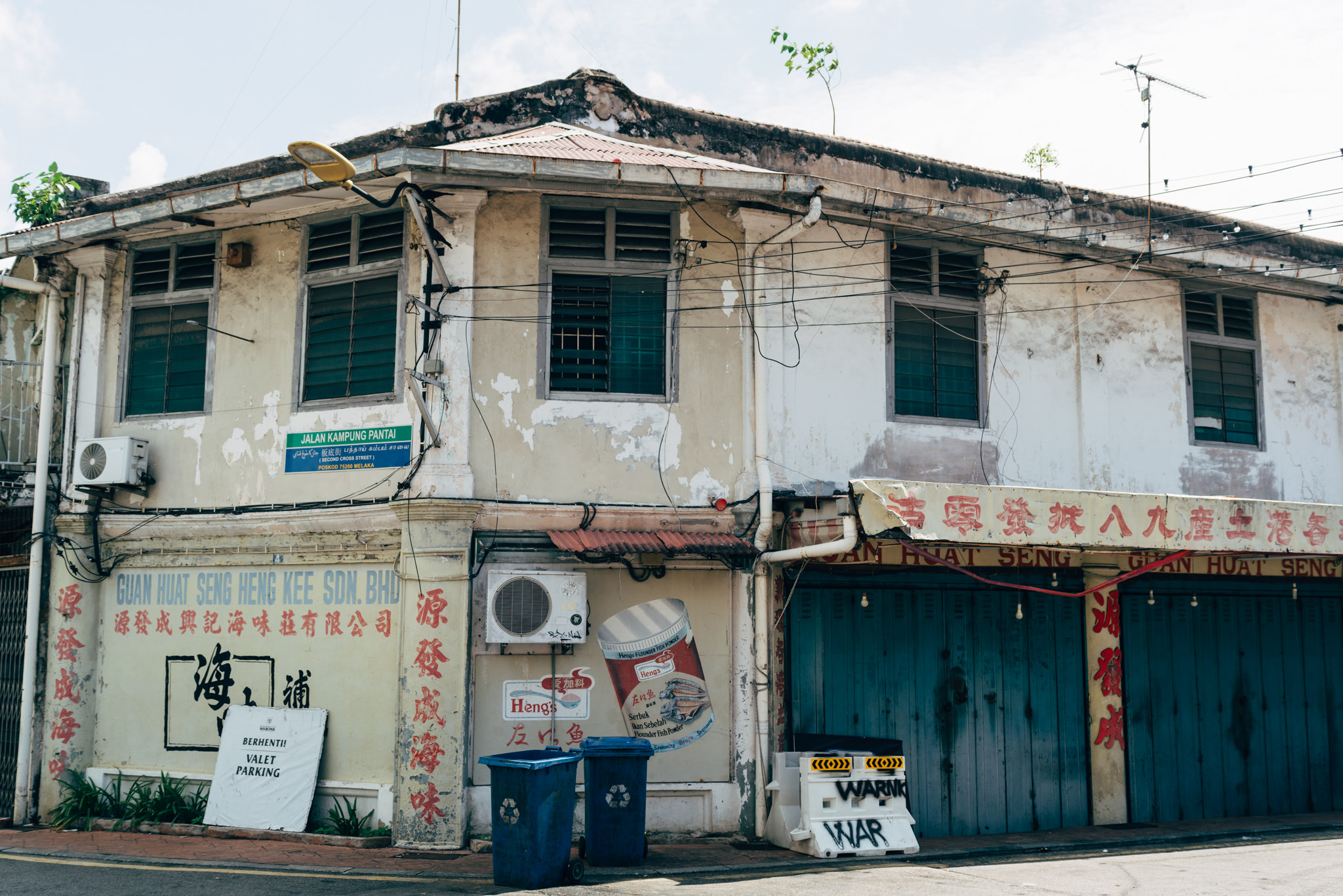 Distressed, multi-story building in Malacca, Malaysia, with faded signage and Chinese characters.