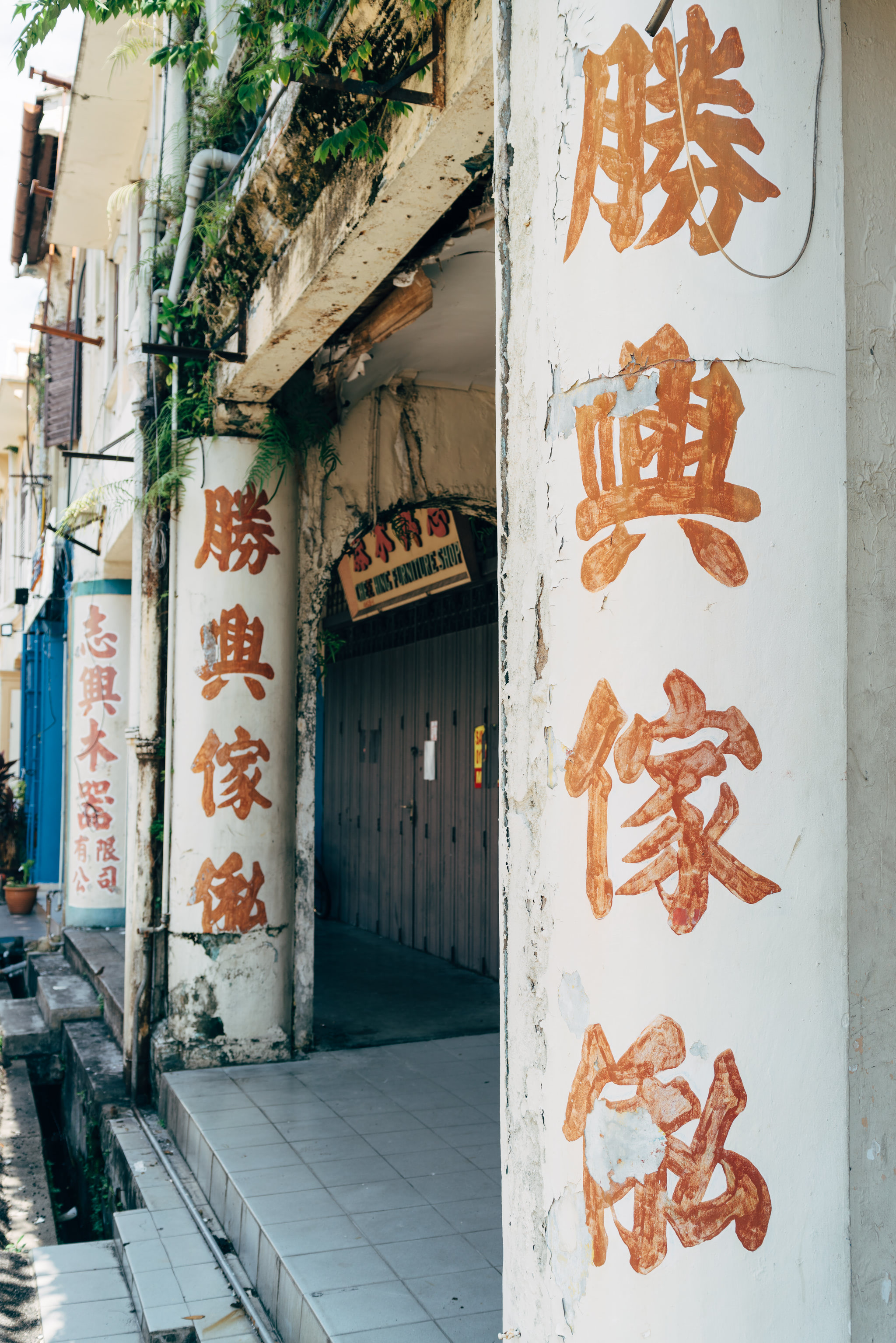 Weathered building facade in Malacca, Malaysia, with faded Chinese characters painted on the walls.